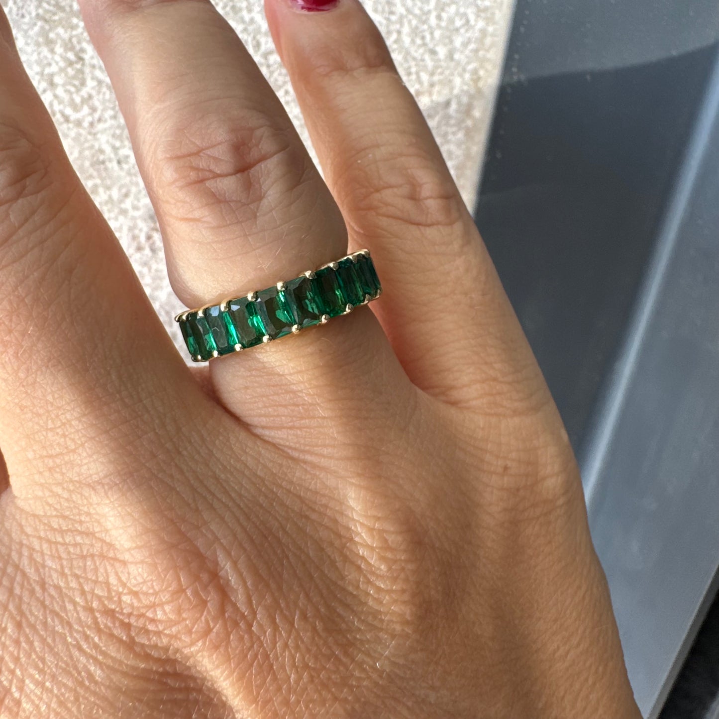 טבעת זהב צהוב 14 קראט משובצת אבנים ירוקות בחיתוך אמרלד, בעיצוב חצי איטרניטי.