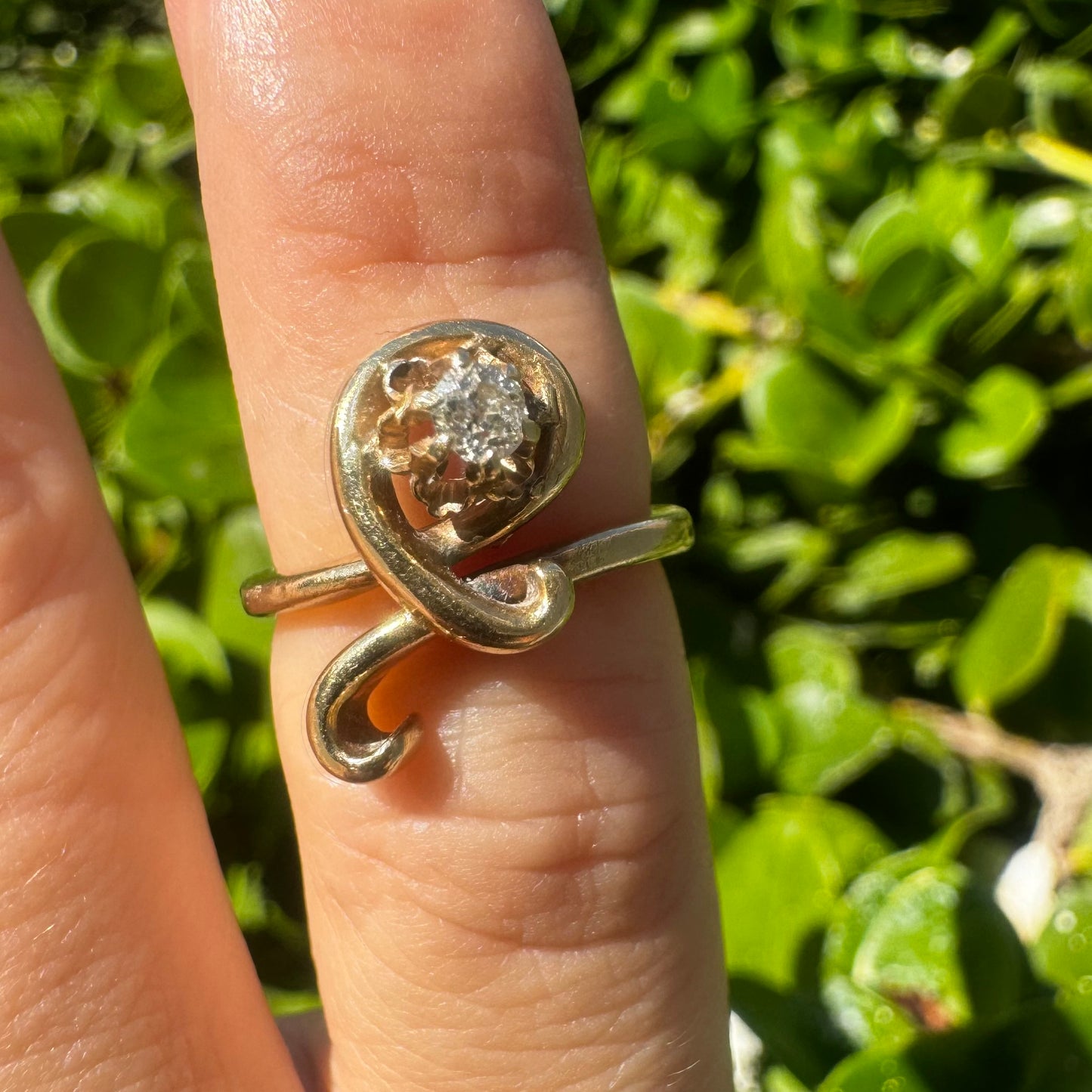 טבעת זהב צהוב 14 קראט משובצת יהלום מרכזי בעיצוב פיסולי וזורם.