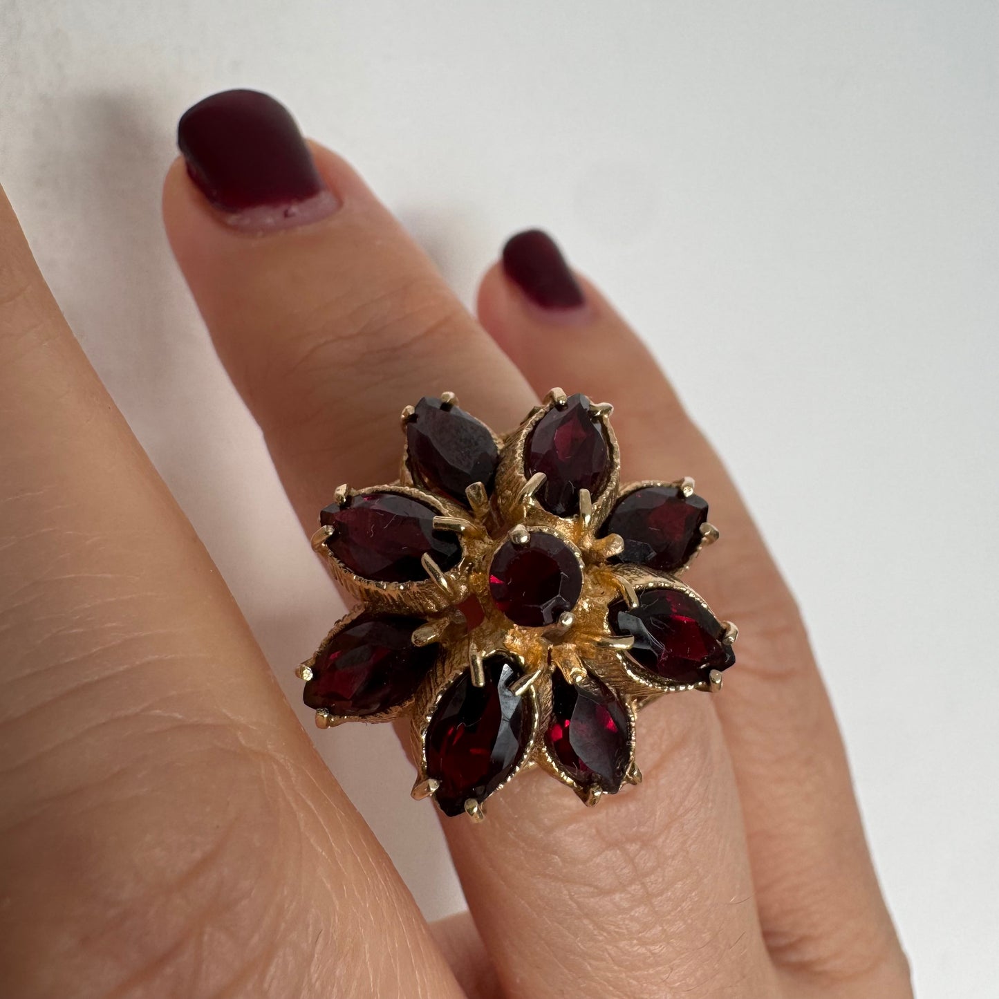 14K gold ring set with marquise-cut Garnets surrounding a round central stone.