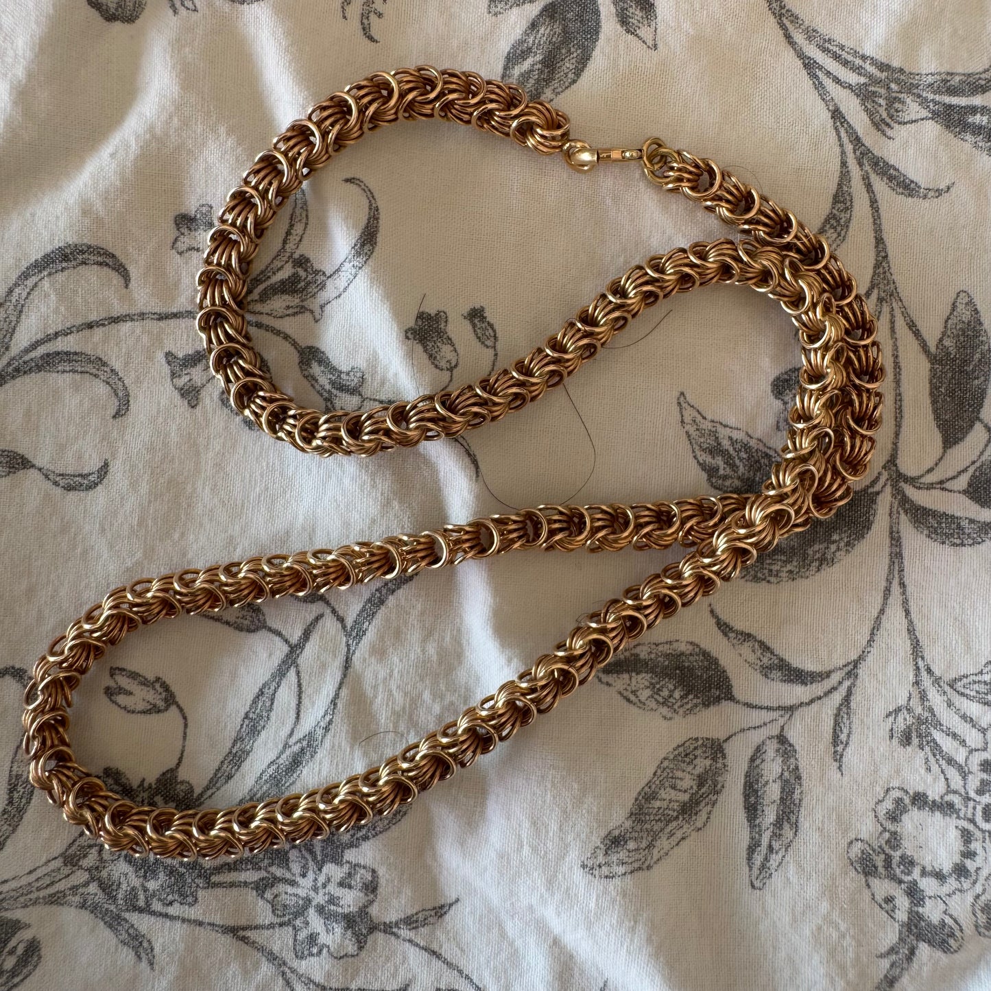 14K gold necklace featuring intricate, interwoven links that create a rich and textured look.