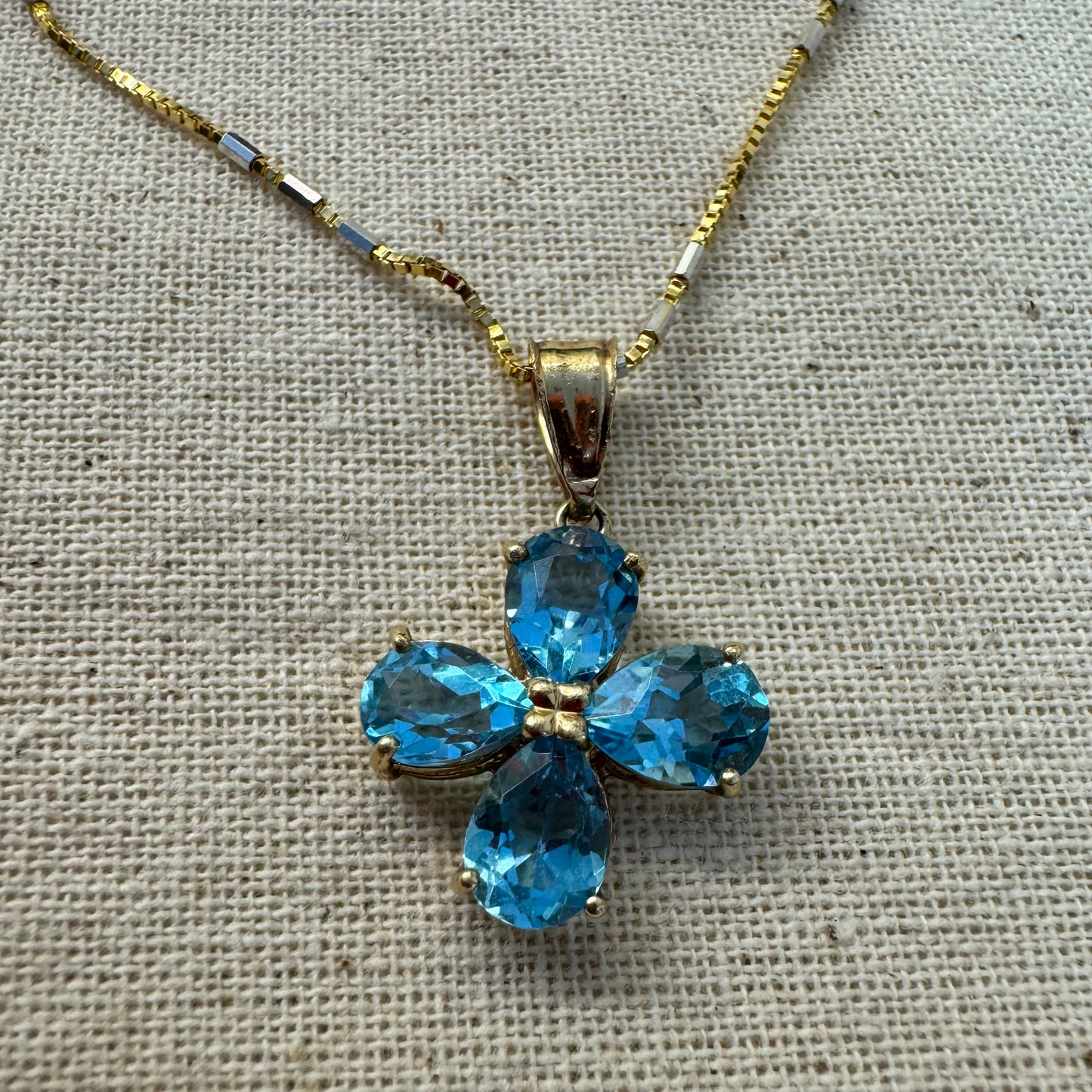 14K gold necklace with a cheerful floral pendant crafted from four pear-shaped Blue Topaz gemstones, arranged in a radiant blossom design