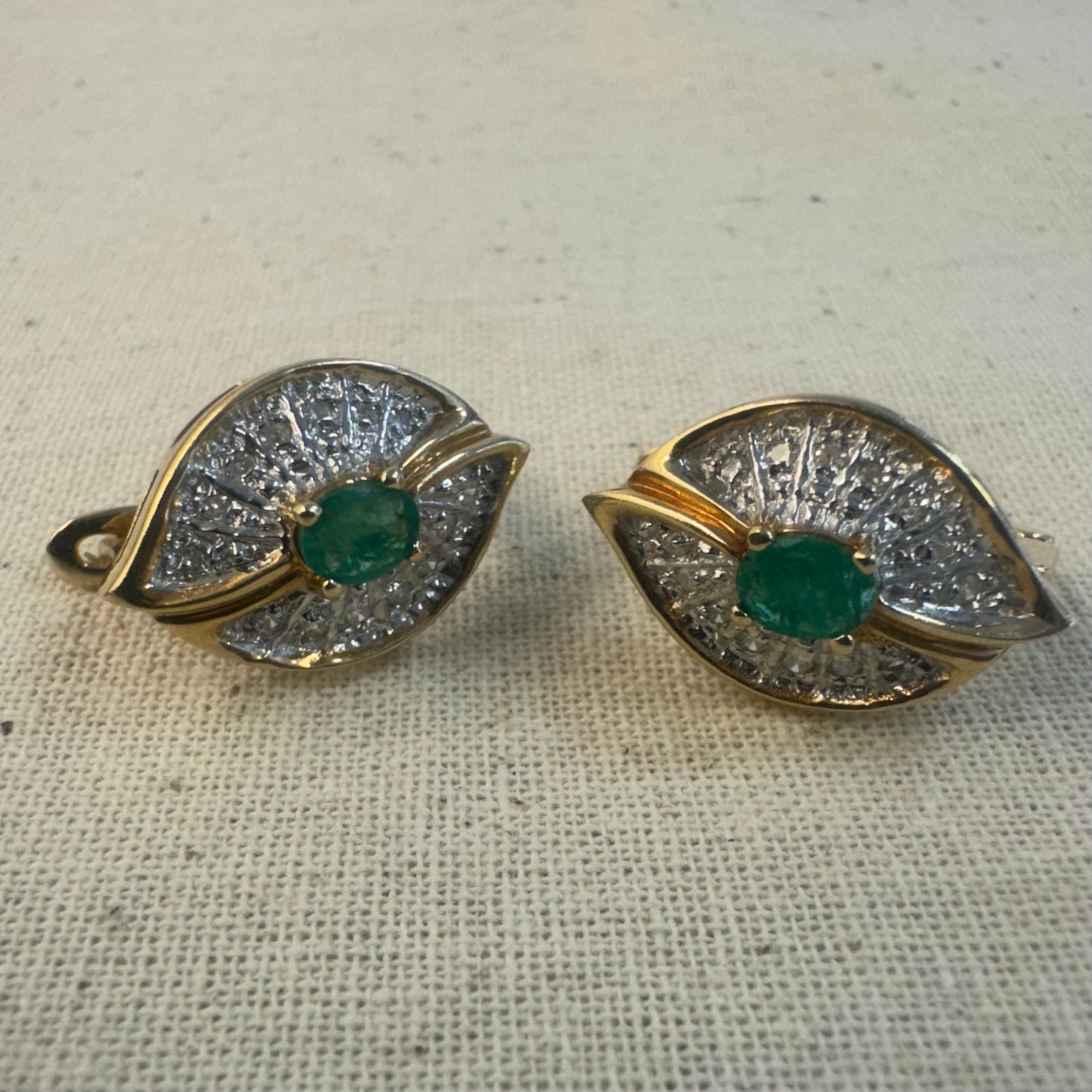 14K gold drop earrings in a refined leaf design, set with vivid green Emeralds at the center and shimmering pavé-set Diamonds along the curves