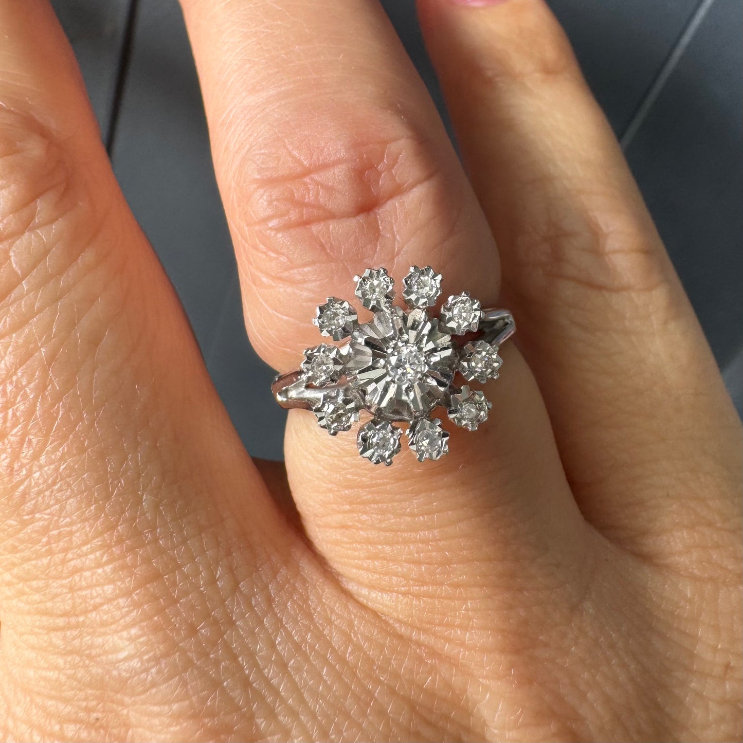 טבעת זהב 18 קראט משובצת יהלום מרכזי מוקף יהלומים נוספים בעיצוב פרח סימטרי ומרשים