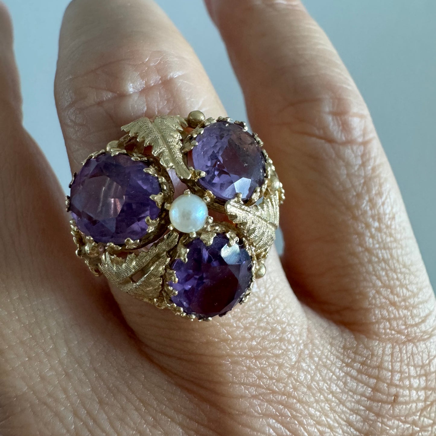 14K gold ring set with four glowing Amethyst stones encircling a delicate central Pearl.