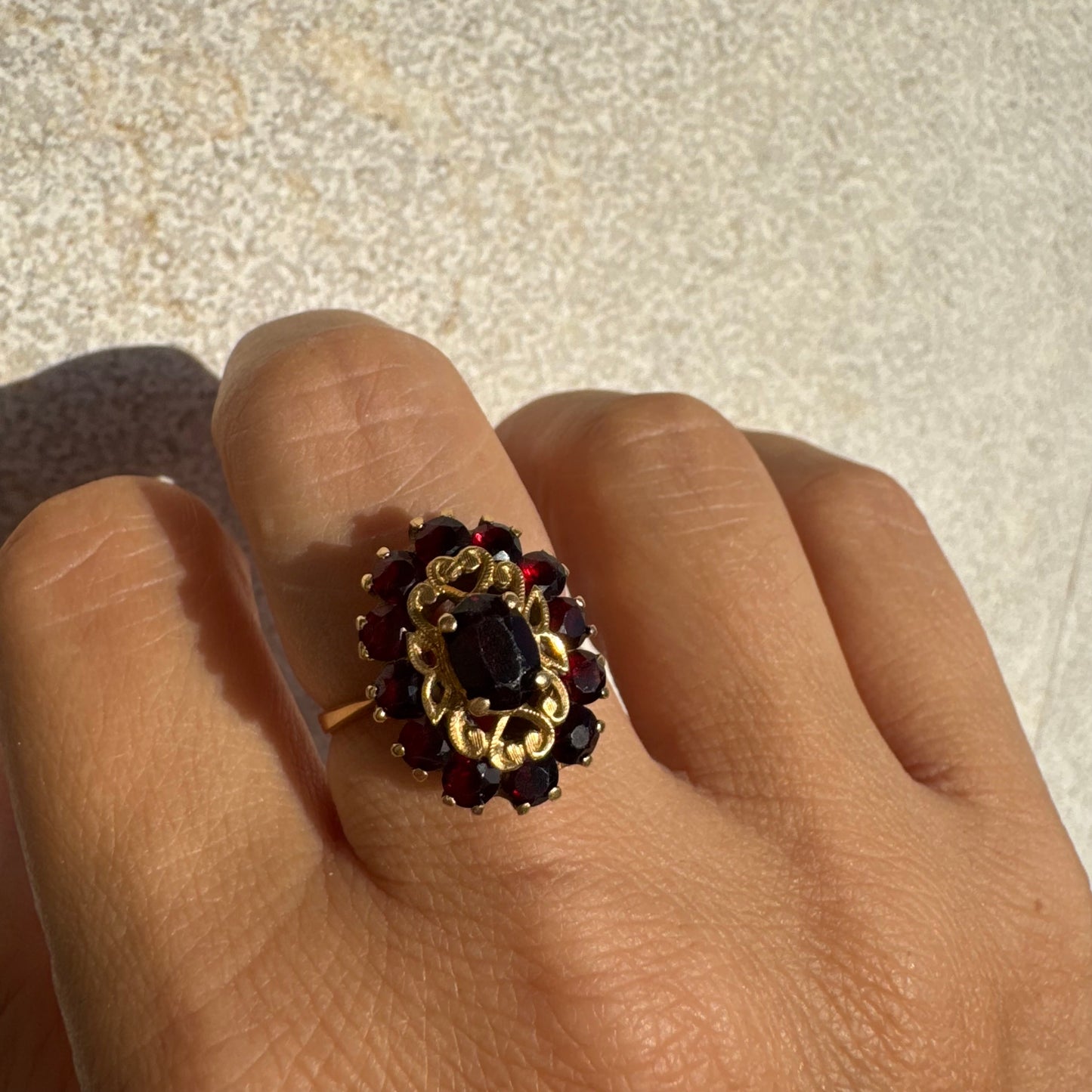 18K gold ring adorned with deep red Garnet gemstones, arranged in a radiant oval composition