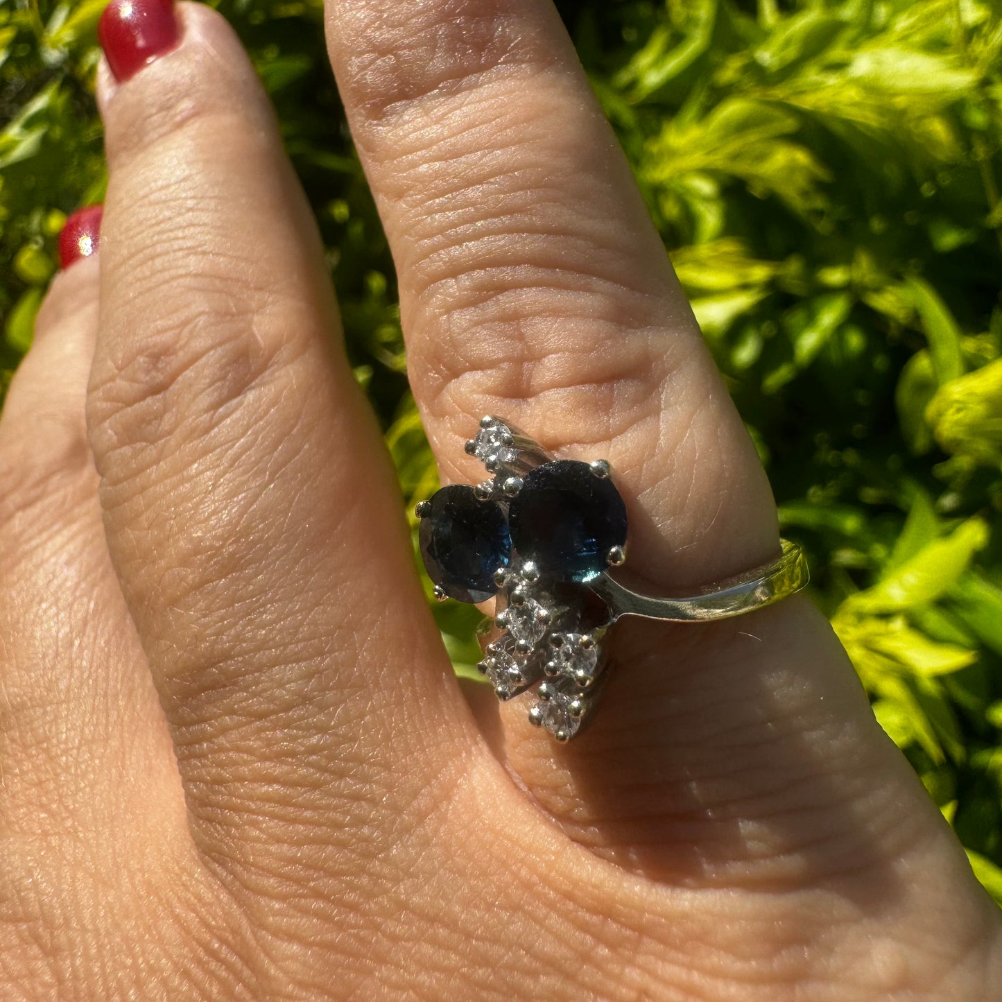 14K gold ring set with two deep blue oval Sapphires accented by clusters of brilliant white Diamonds.