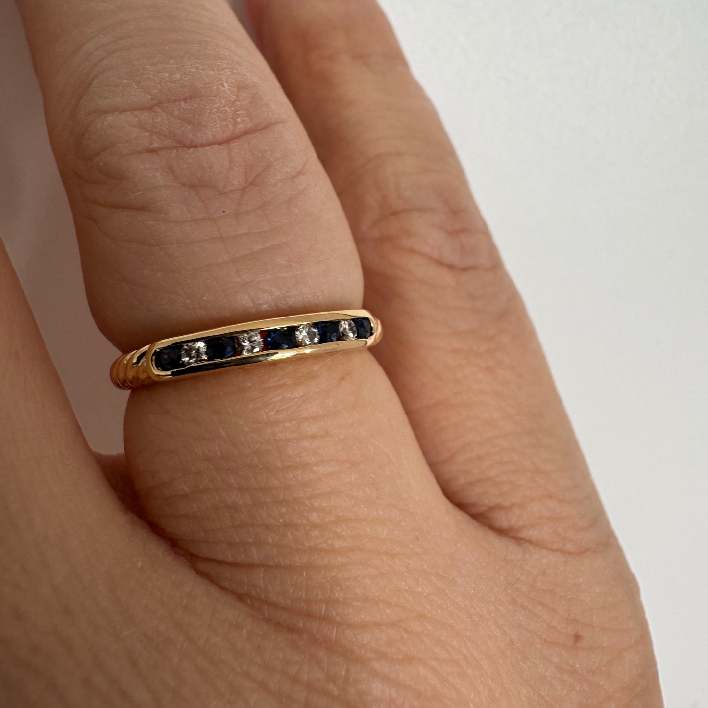 18K gold ring featuring a refined channel setting of deep blue Sapphires accented with Diamonds.