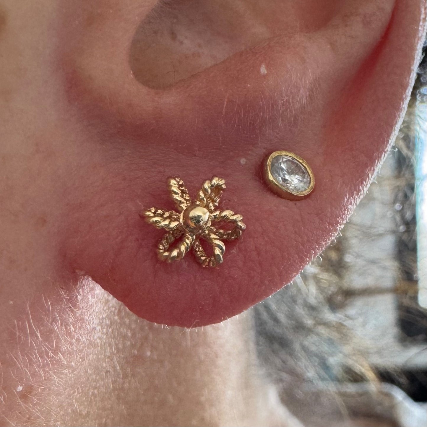 14K gold stud earrings designed as miniature flowers with fine textured details.