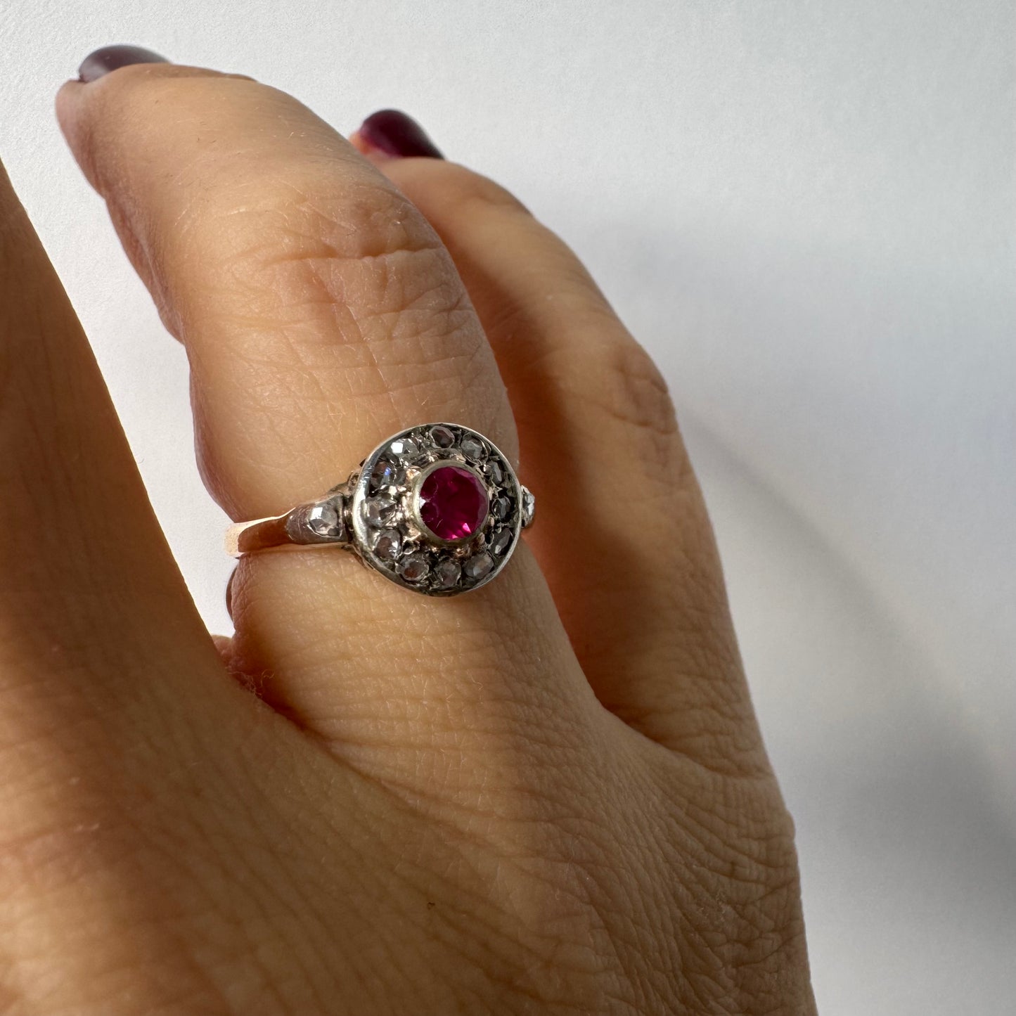18K gold ring set with a round Ruby at the center, surrounded by a halo of old-cut Diamonds.