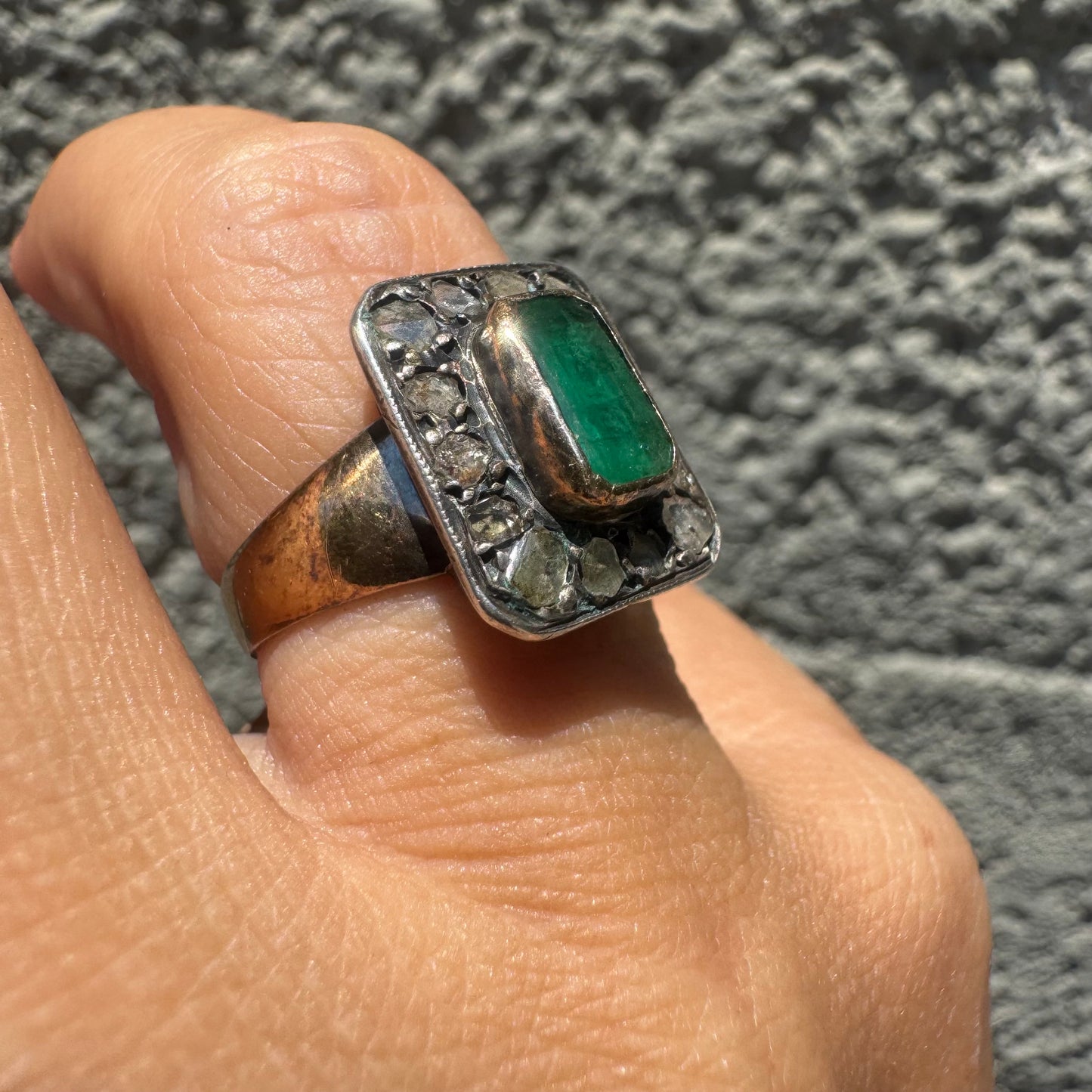 18K gold ring set with a rectangular Emerald and framed by a halo of rose-cut Diamonds