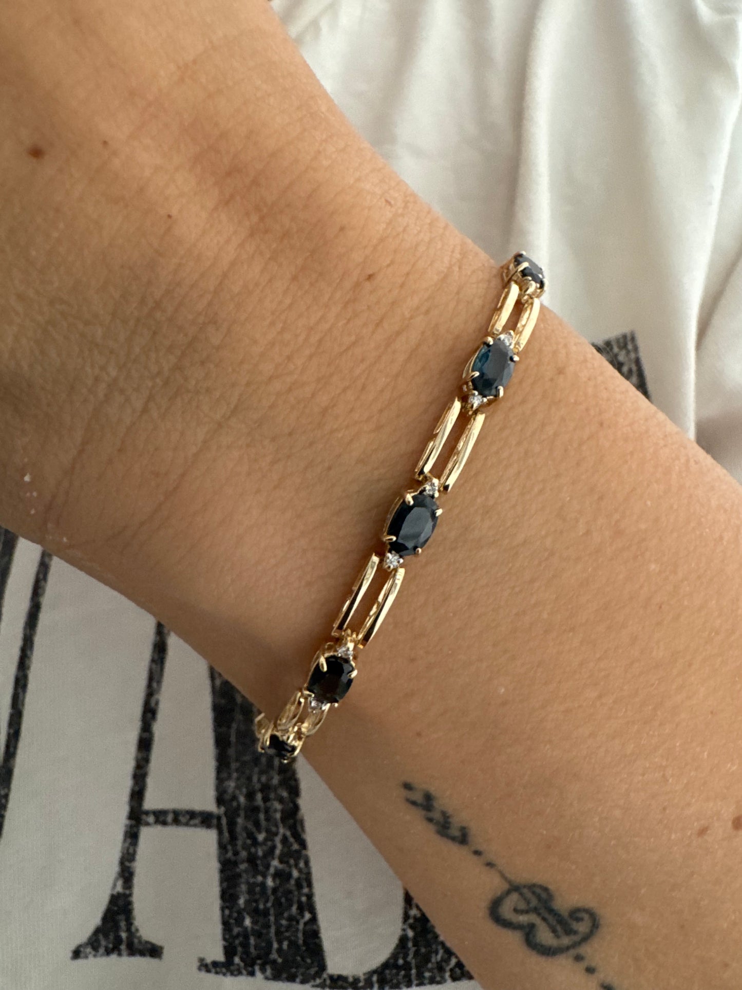 צמיד זהב צהוב 14 קראט משובץ אבני טופז כחולות בחיתוך אובלי, עם יהלומים המשובצים ביניהן להוספת ברק עדין.