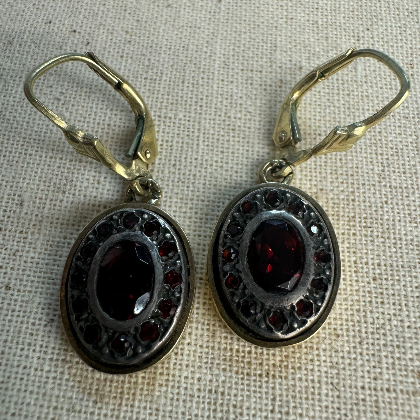 14K gold drop earrings set with deep red oval Garnets surrounded by smaller stones Garnets.