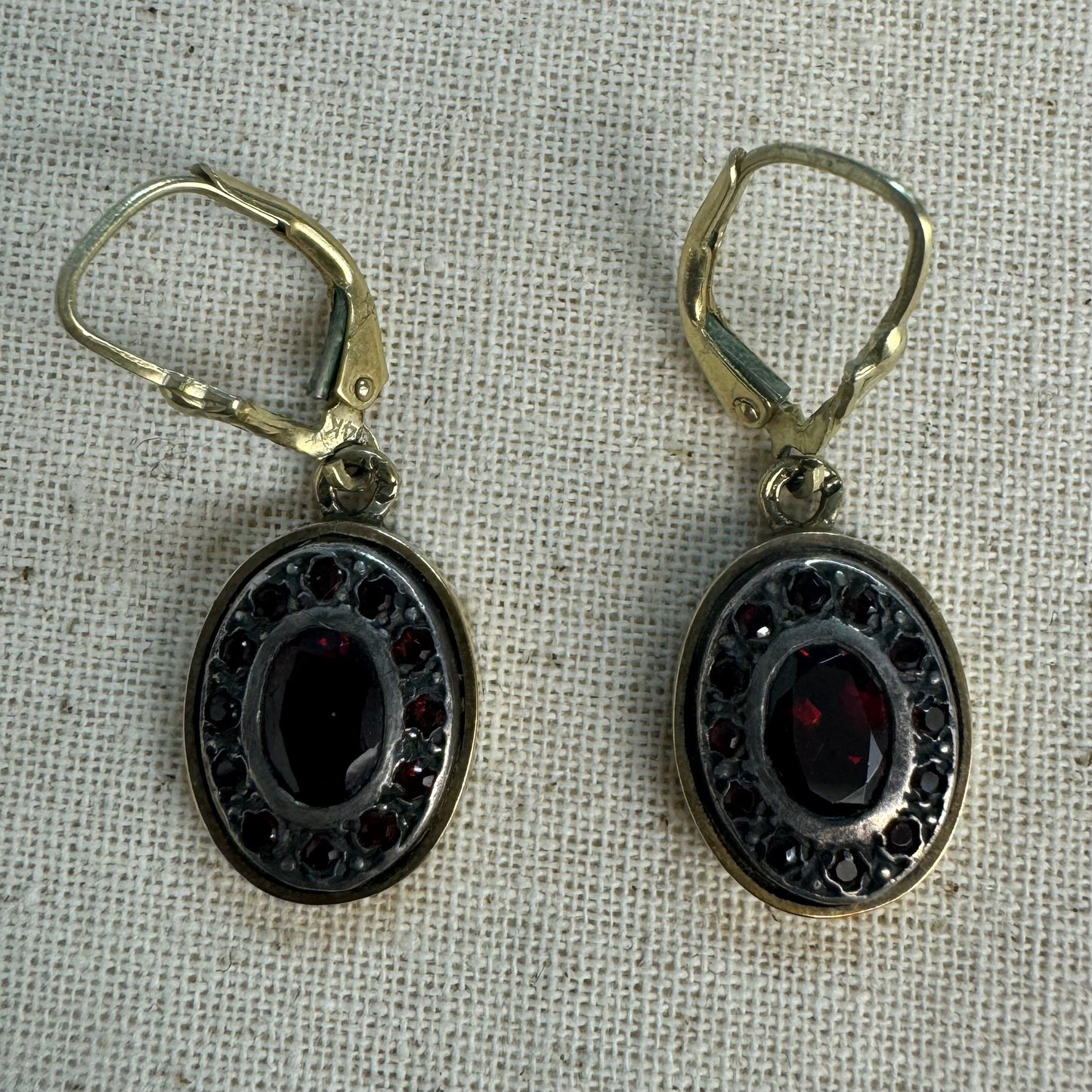 14K gold drop earrings set with deep red oval Garnets surrounded by smaller stones Garnets.