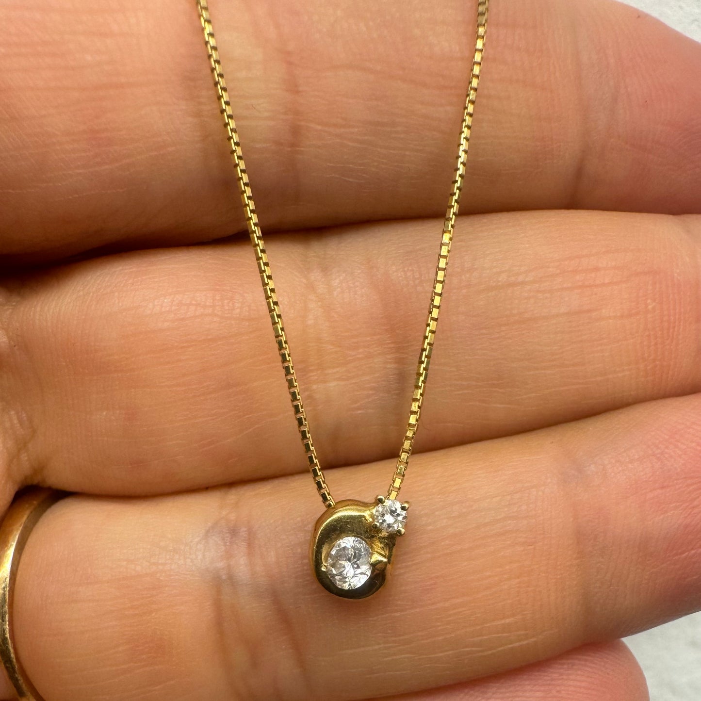 18K gold necklace set with a modern round pendant set with two brilliant-cut Diamonds in different sizes