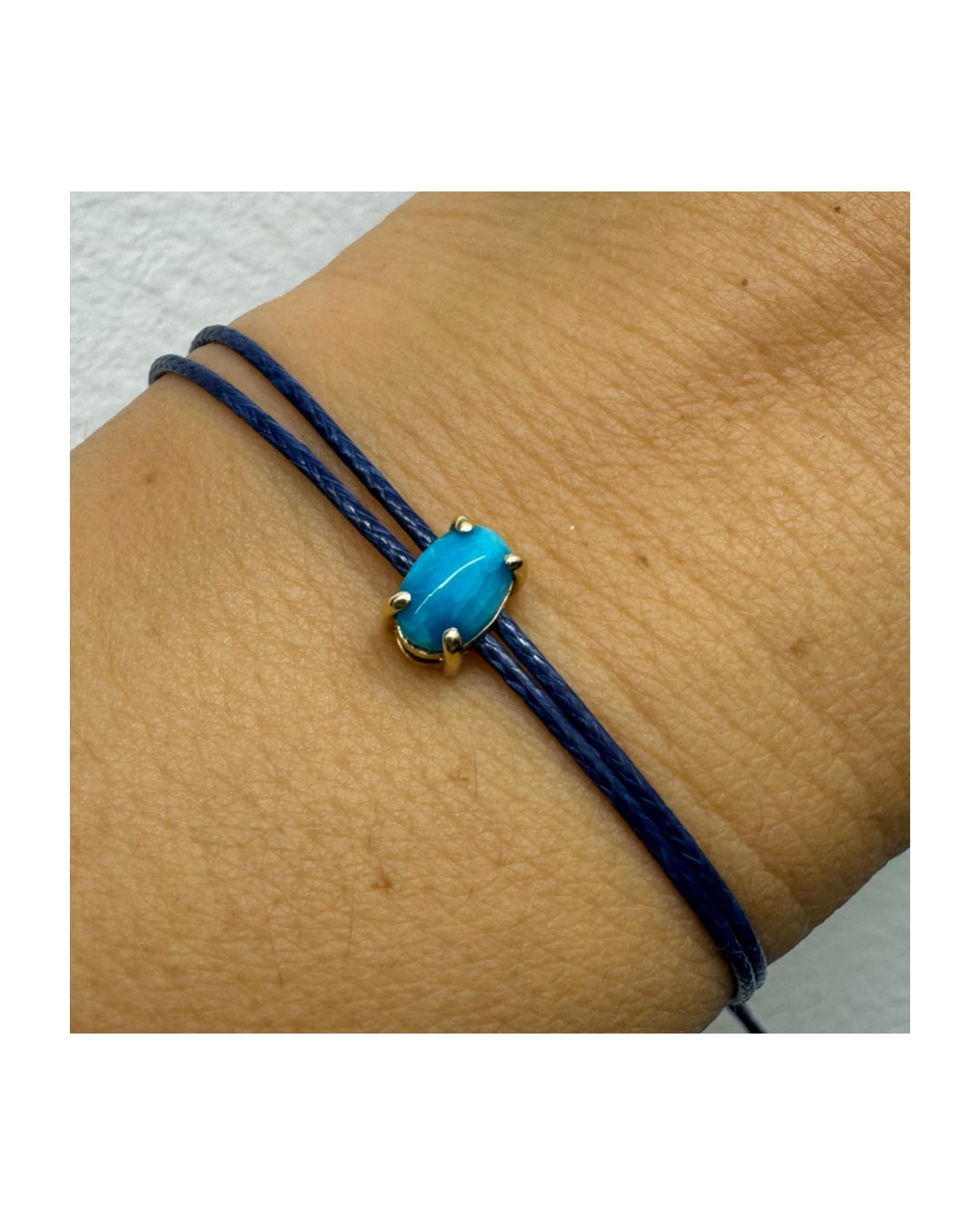 צמיד חוט כחול עדין עם אבן טורקיז טבעית בגוון כחול עמוק, משובצת במסגרת זהב.