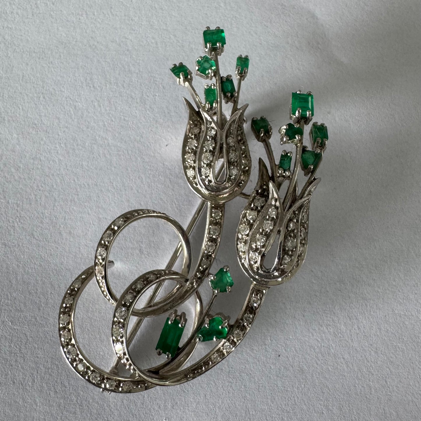 18K gold vintage brooch featuring an elegant floral design set with vibrant Emeralds and sparkling Diamonds.