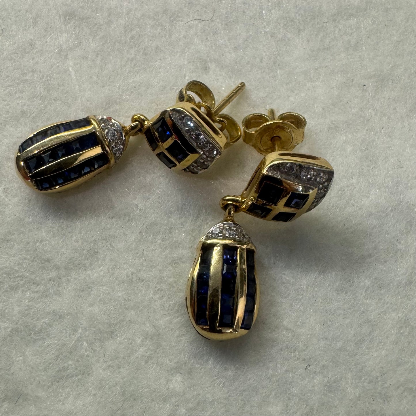18K old drop earring set with deep blue Sapphires in a geometric pattern, accented with sparkling Diamonds.