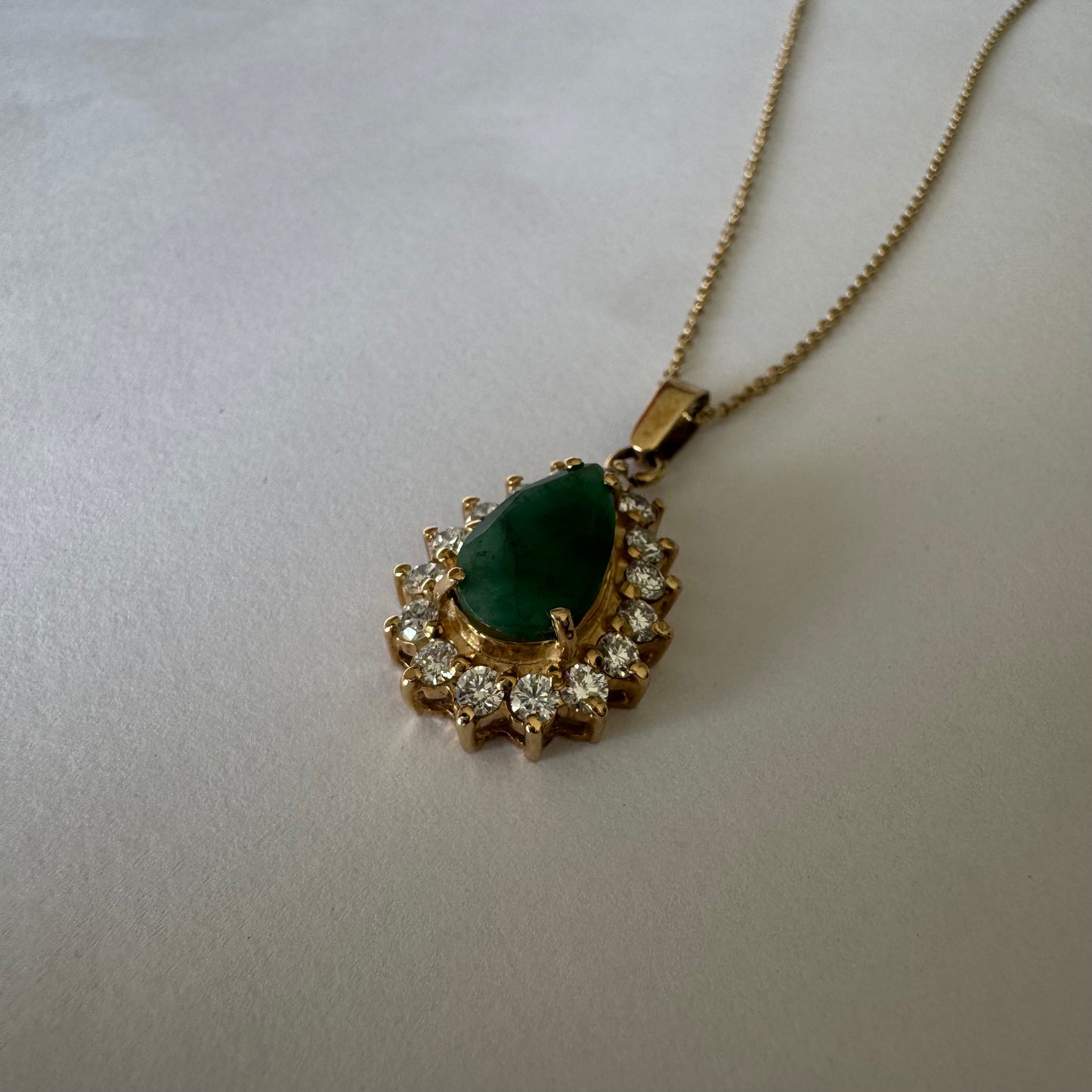 14K gold necklace set with a pear-cut Emerald, surrounded by sparkling lab-grown Diamonds.