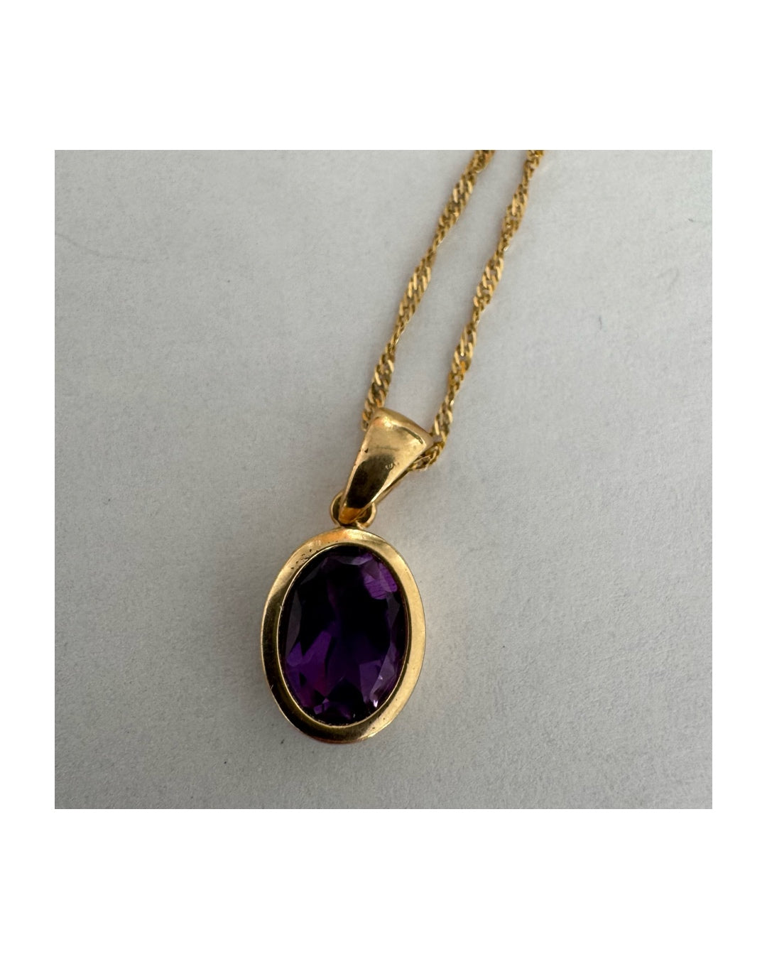 14K yellow gold necklace set with an oval-cut Amethyst in a smooth, classic bezel setting.