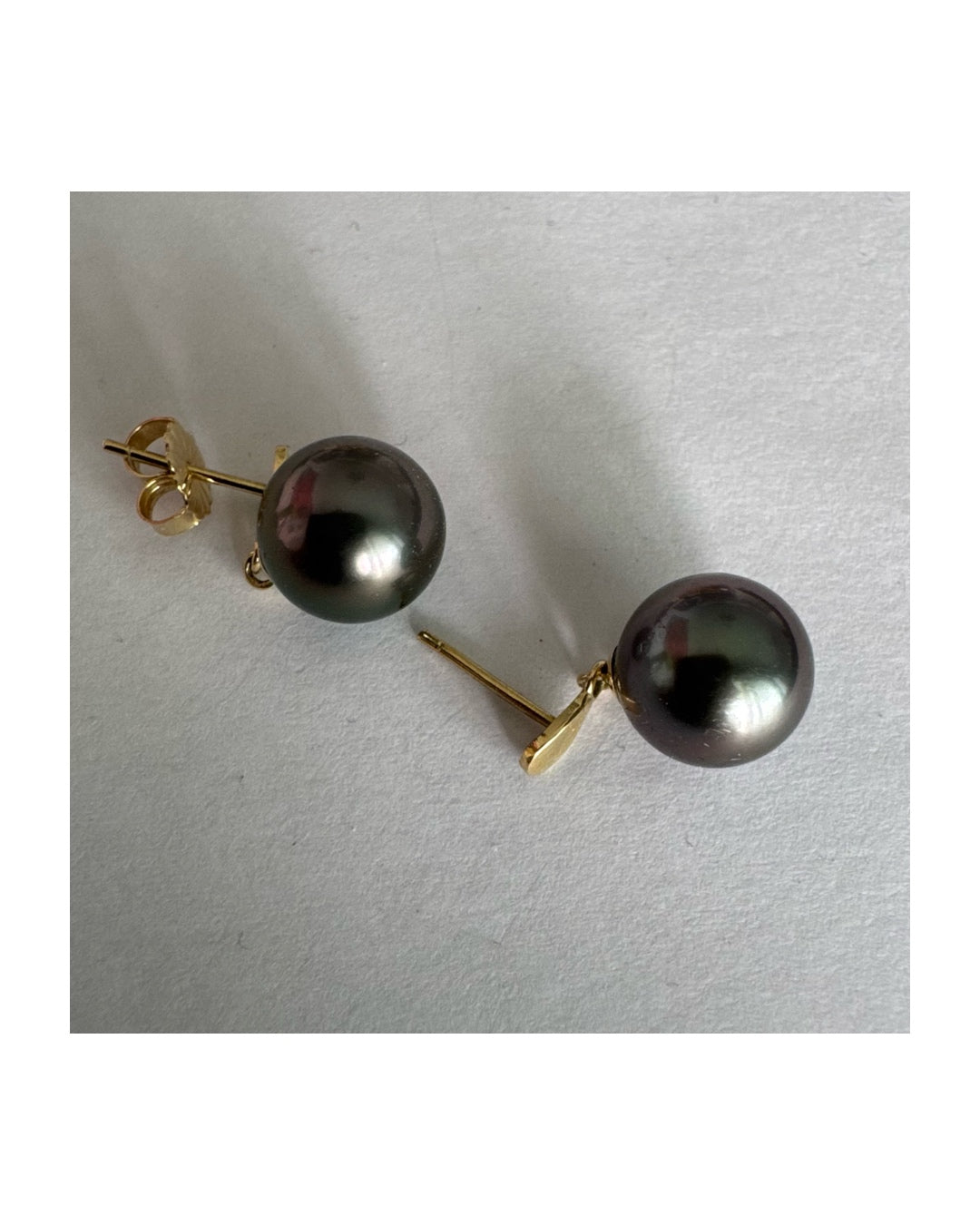 עגילי זהב צהוב 14 קראט משובצים פנינים עגולות בגוון כהה עם ברק עמוק ומשתנה.