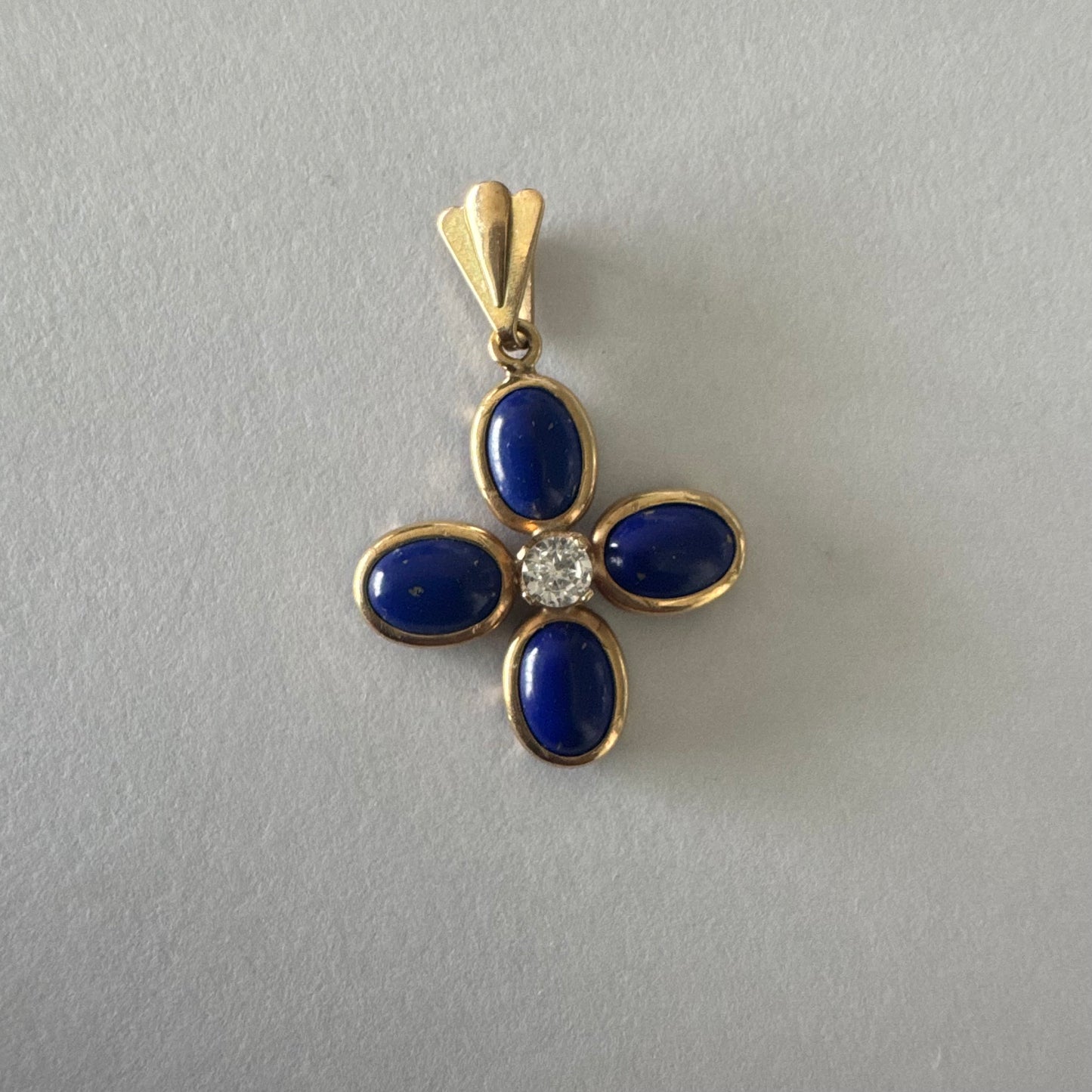תליון זהב צהוב 14 קראט בעיצוב פרח סימטרי, משובץ ארבע אבני לפיס לזולי בגימור קבושון אובלי ובמרכזן יהלום עגול בוהק.
