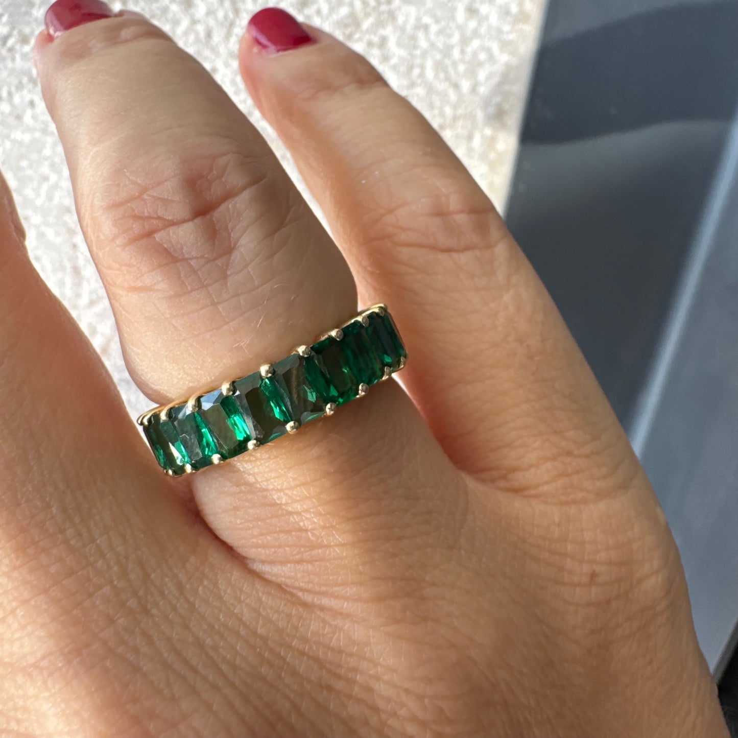 טבעת זהב צהוב 14 קראט משובצת אבנים ירוקות בחיתוך אמרלד, בעיצוב חצי איטרניטי.