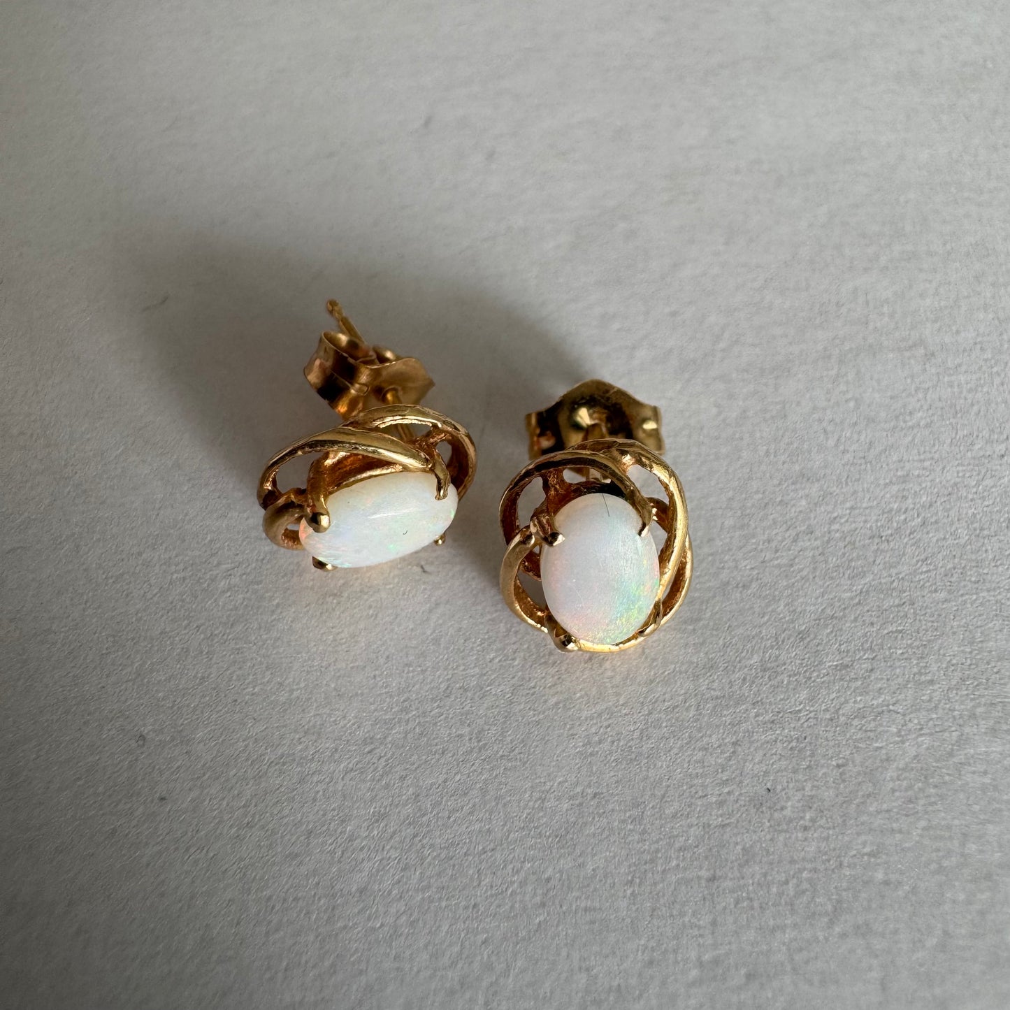 עגילי זהב צהוב 14 קראט משובצים אבני אופל אובליות בגוון לבן חלבי עם משחקי צבע טבעיים ועדינים.