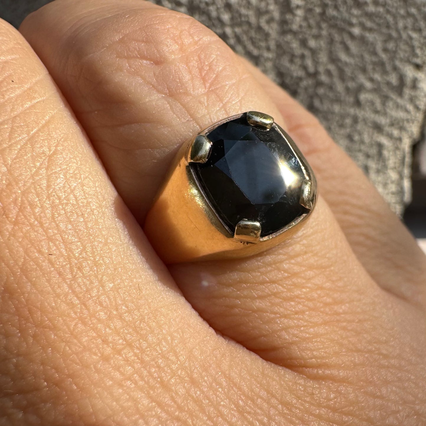 טבעת זהב 9 קראט משובצת ספיר ירוק כהה בחיתוך כרית ובתפסים עבים, בעיצוב נקי ובעל נוכחות. 