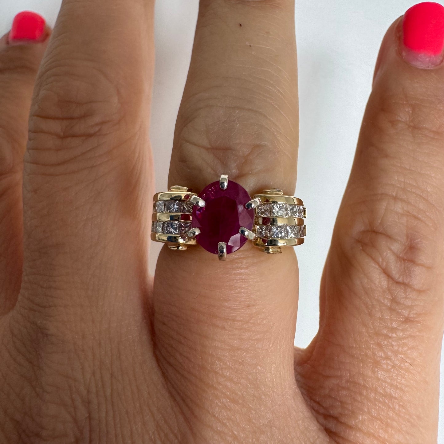 14K gold ring set with a vivid natural Ruby at the center and accented by rows of Diamonds on both sides.