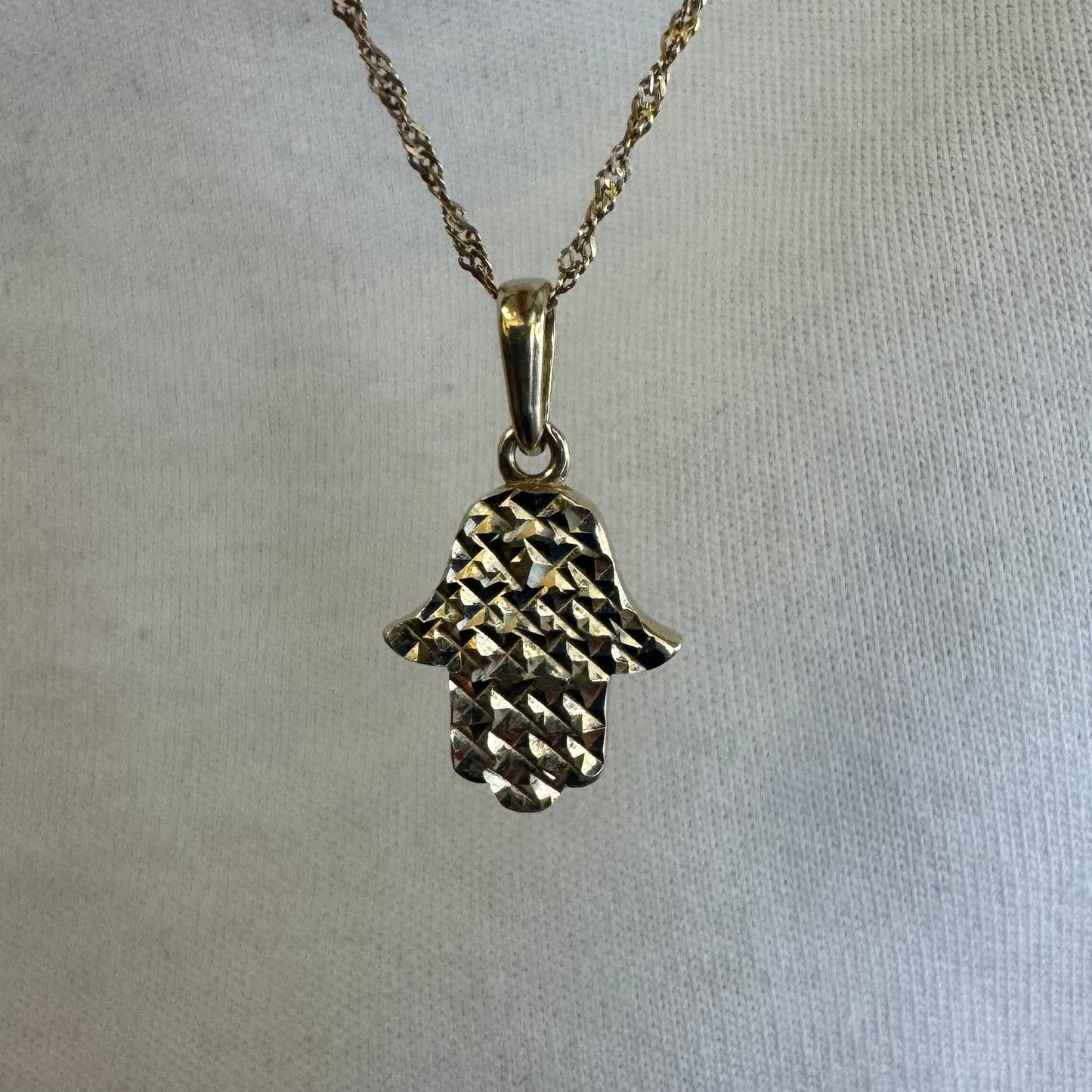 14K gold Hamsa pendant featuring a richly textured, light-catching finish.