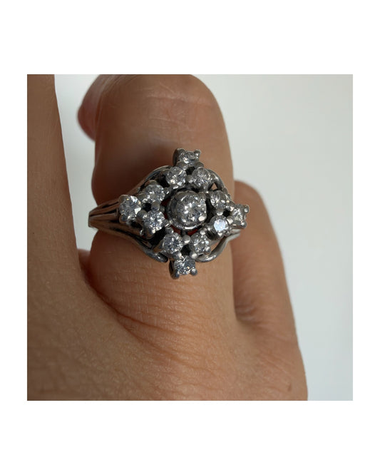 טבעת פלטינה משובצת יהלום עגול במרכז מוקף ביהלומים נוספים.