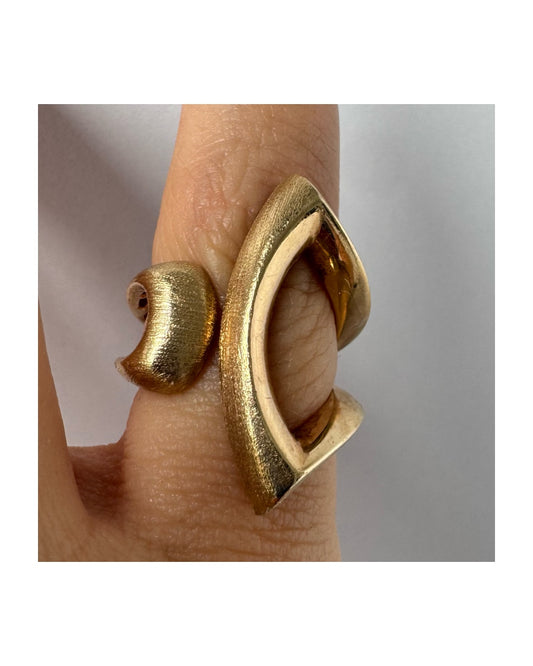 14K gold sculptural ring with a bold, modern design featuring flowing, asymmetrical lines.