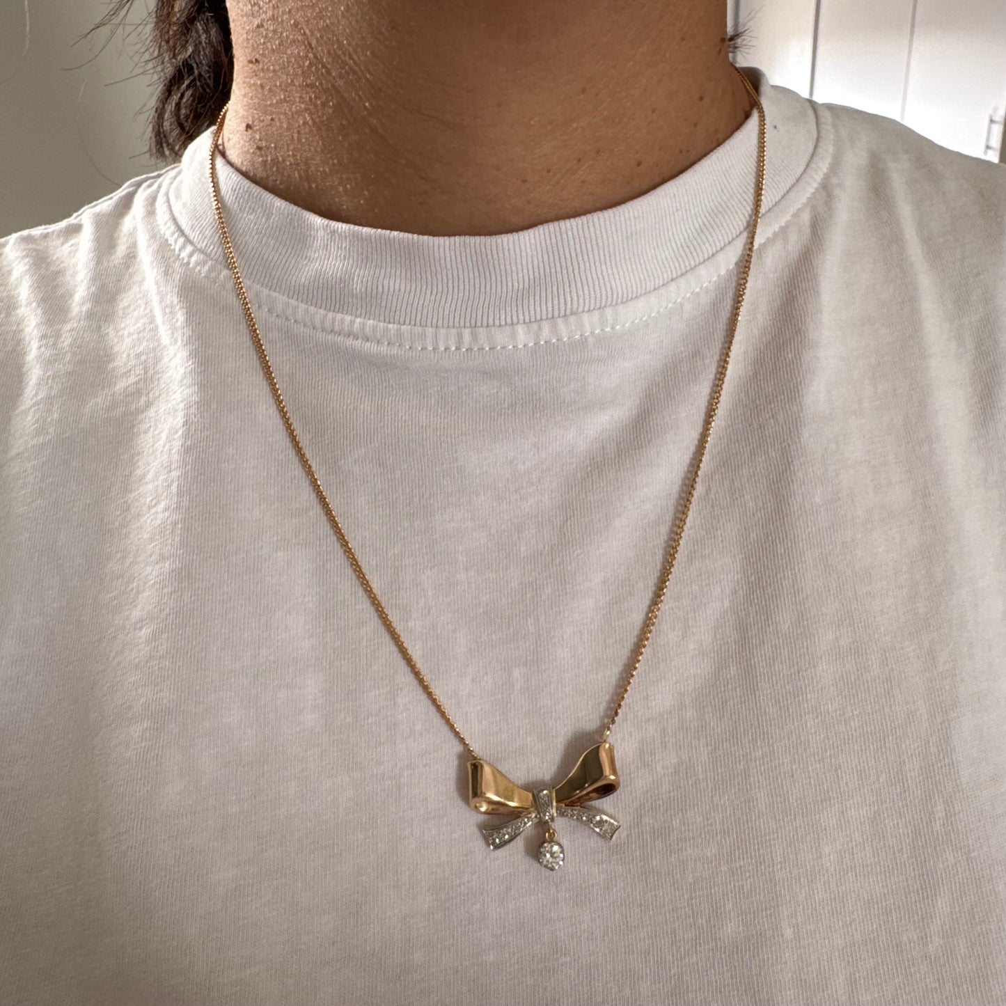 שרשרת זהב 18 קראט עם תליון בצורת סרט קלאסי משובץ יהלומים ונושא יהלום מרכזי תלוי שמוסיף נגיעה של זוהר ואלגנטיות