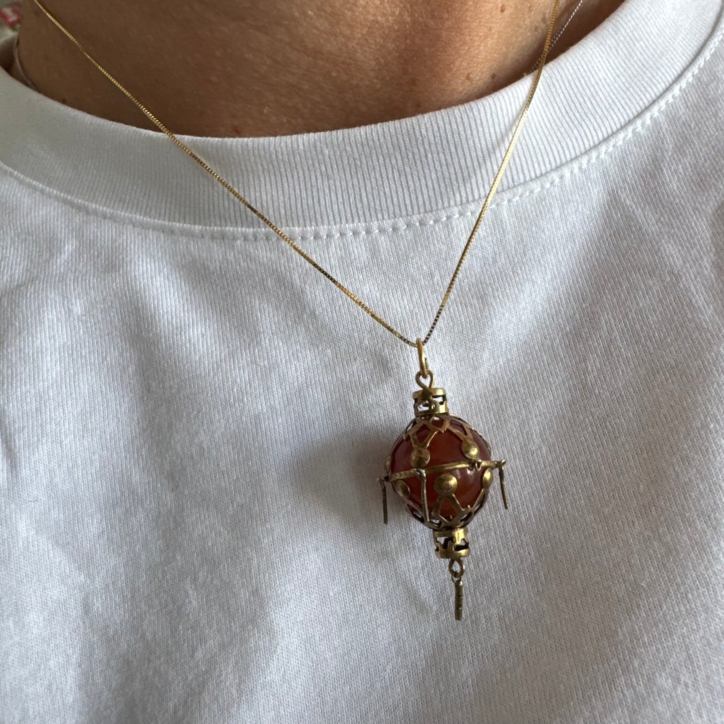 9K gold pendant set with a deep red stone in an intricate openwork design.