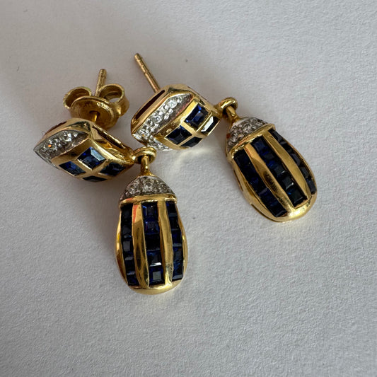 18K gold drop earring set with deep blue Sapphires in a geometric pattern, accented with sparkling Diamonds.