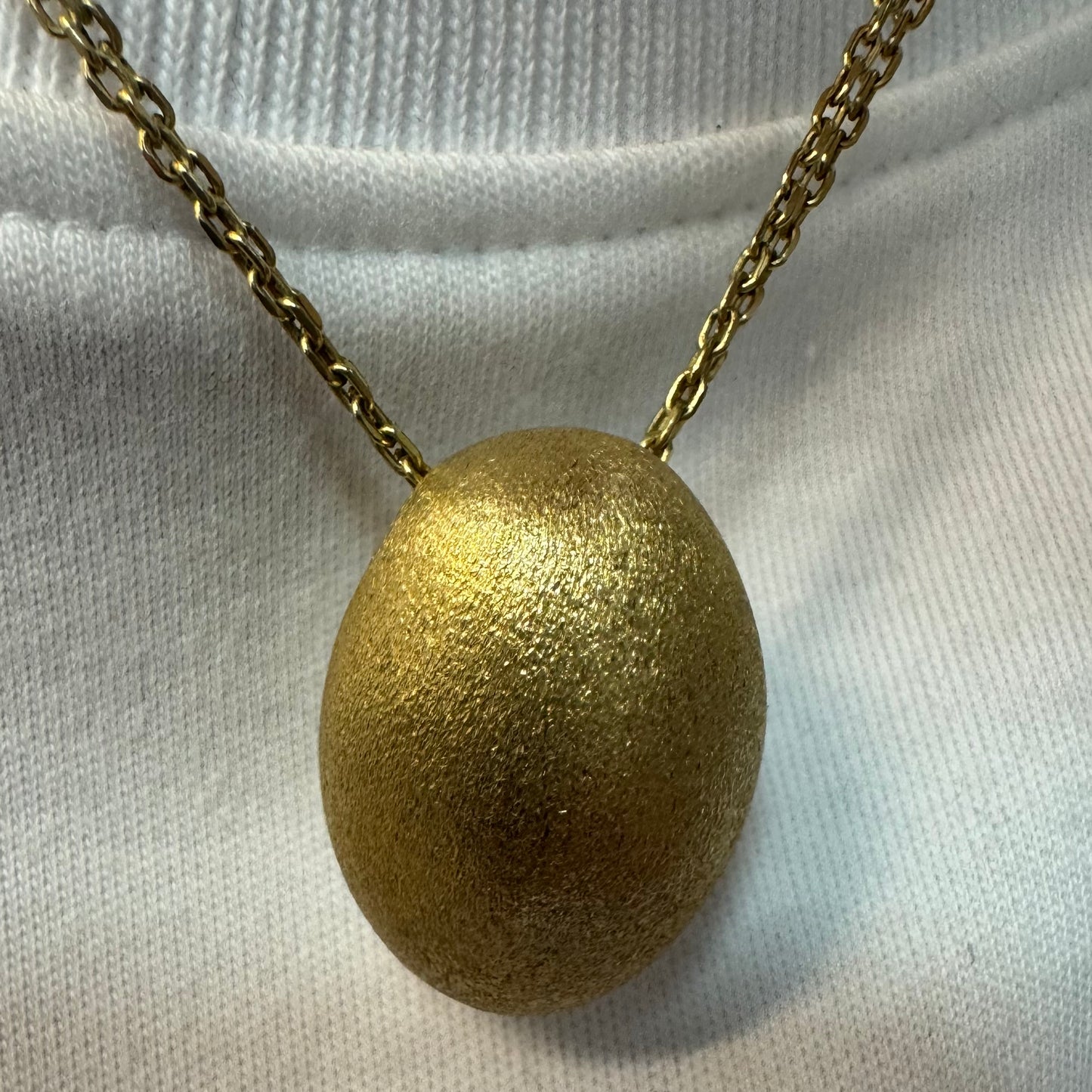 An elegant H.Stern 18K gold necklace featuring a bold oval pendant with a softly textured matte finish. 
(Golden Stones collection)