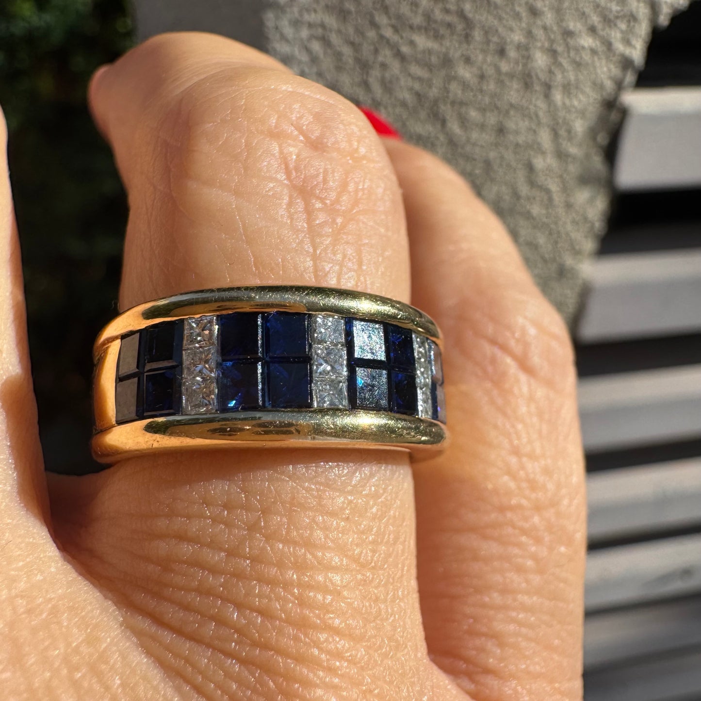 טבעת ה.שטרן זהב צהוב 18 קראט, בעיצוב רחב ומרשים. משובצת שורת אבני ספיר כחולות מרובעות בשילוב מחיצות של יהלומים לנגיעת ברק יוקרתי.