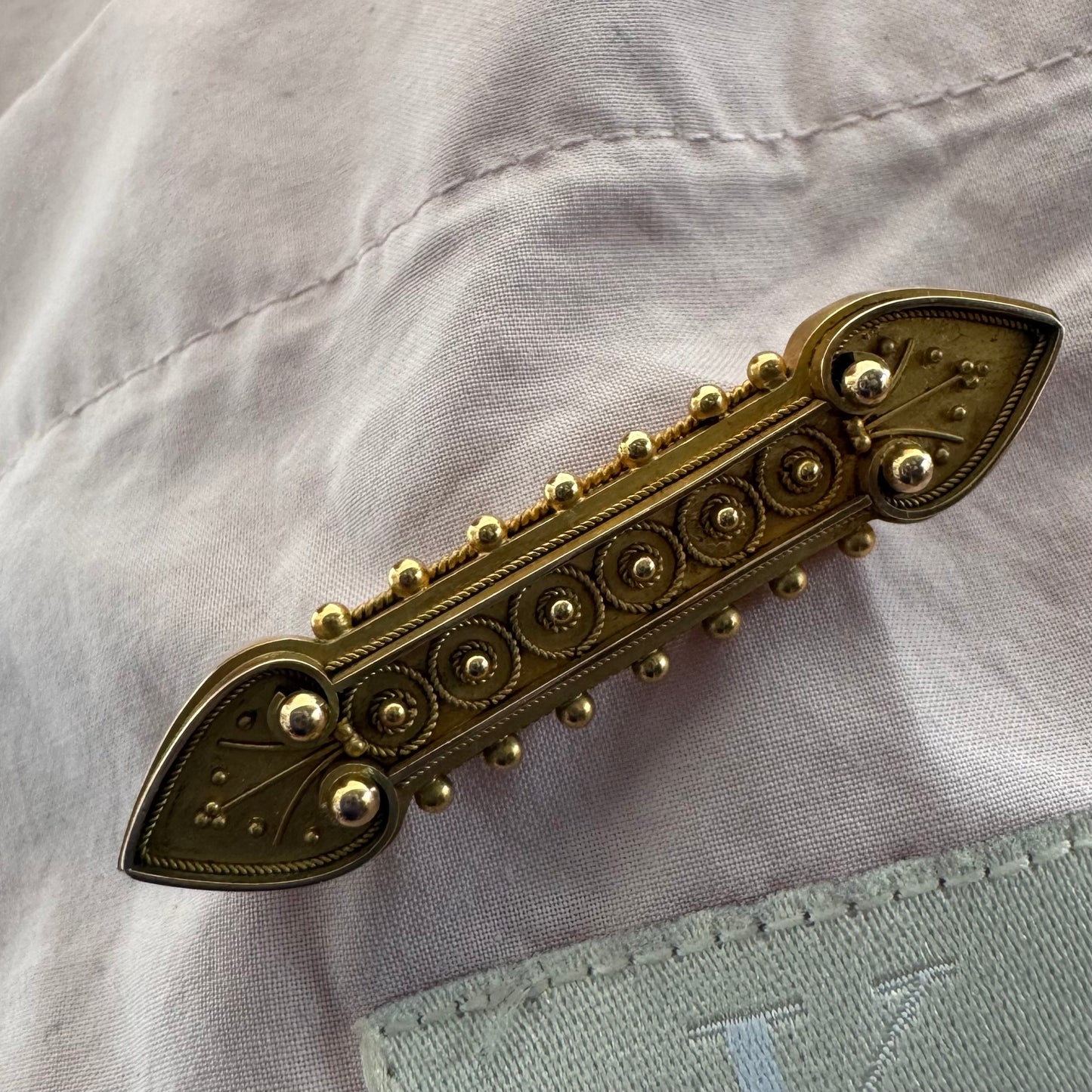 14K gold brooch featuring an ornate geometric design with intricate gold detailing & symmetrical decorative motifs.
