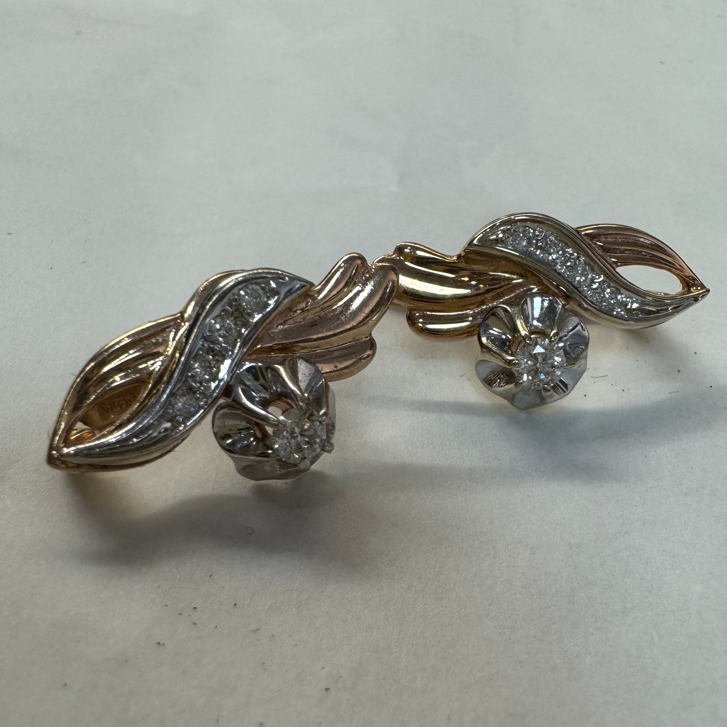 עגילי זהב 14 קראט בעיצוב מתעגל ואלגנטי המשובצים יהלומים נוצצים .