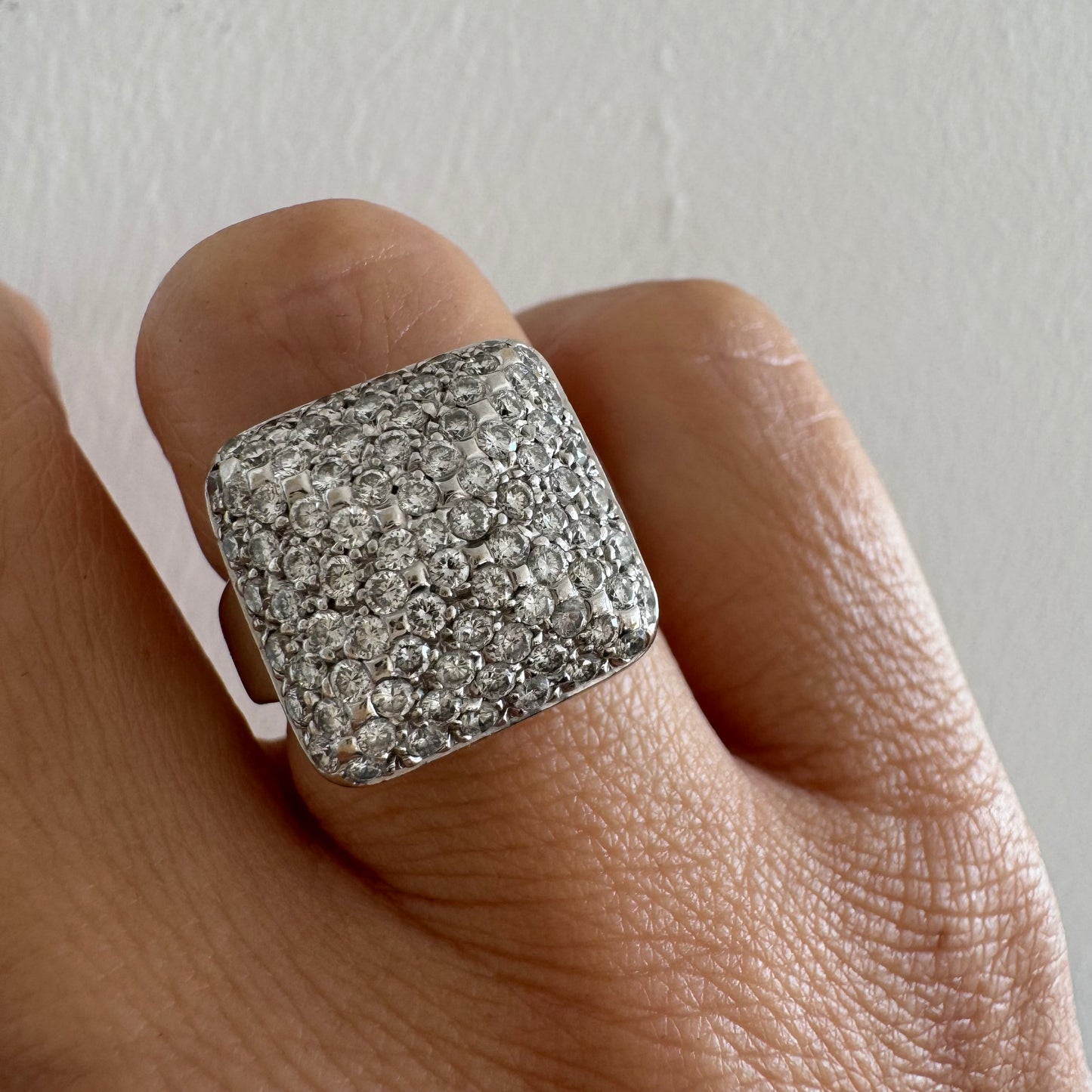 טבעת זהב לבן 18 קראט עם חלק עליון רחב בצורת ריבוע המשובץ כולו ביהלומים מנצנצים, ליצירת מראה יוקרתי ונוצץ.