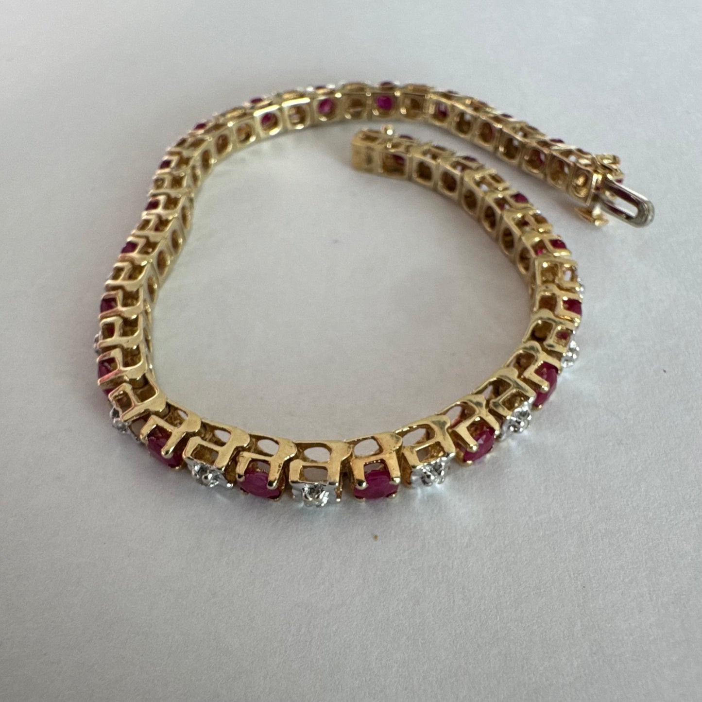 צמיד זהב צהוב 10 קראט משובץ אבני רובי בגוון אדום עמוק וביניהן יהלומים לבנים מנצנצים.