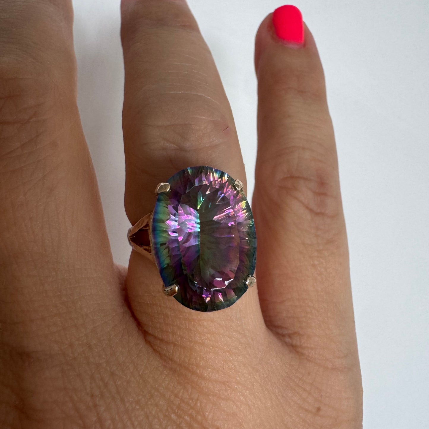 9K gold ring set with a large iridescent stone displaying mesmerizing shades of purple, green, and blue that shift beautifully in the light.