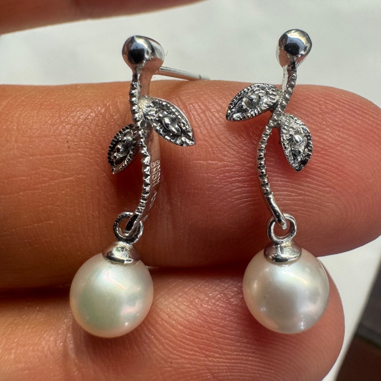 14K gold drop earrings designed with delicate leaf details, each holding a round white Pearl.