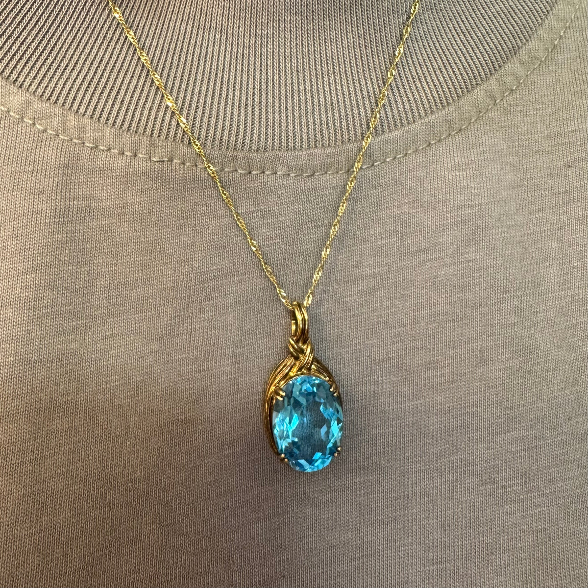 9K gold Pendant set with a striking oval-cut Blue Topaz