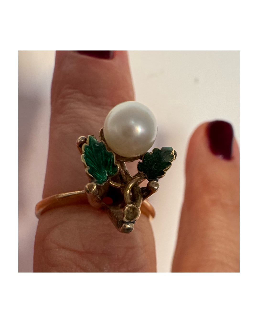 טבעת זהב 14 קראט משובצת פנינה מרכזית ומעוטרת אמייל ירוק בעבודת יד בצורת עלים.