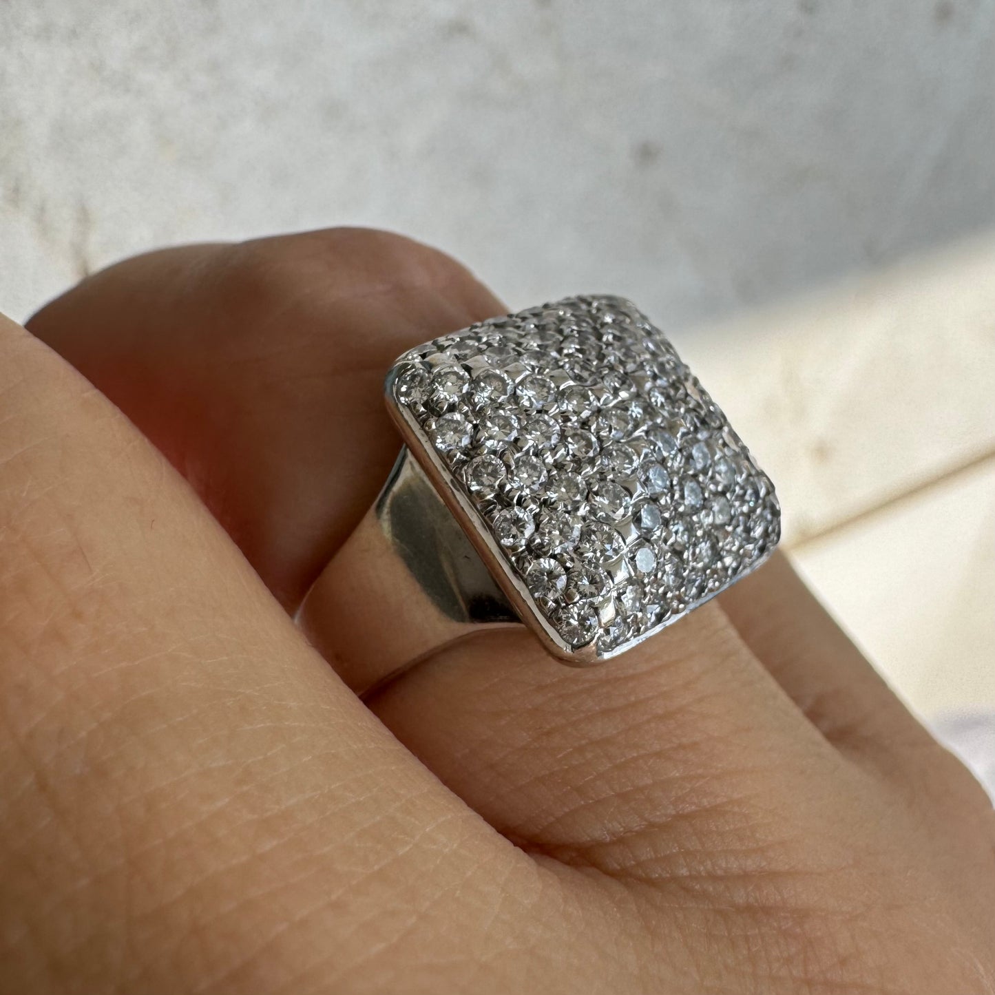 טבעת זהב לבן 18 קראט עם חלק עליון רחב בצורת ריבוע המשובץ כולו ביהלומים מנצנצים, ליצירת מראה יוקרתי ונוצץ.