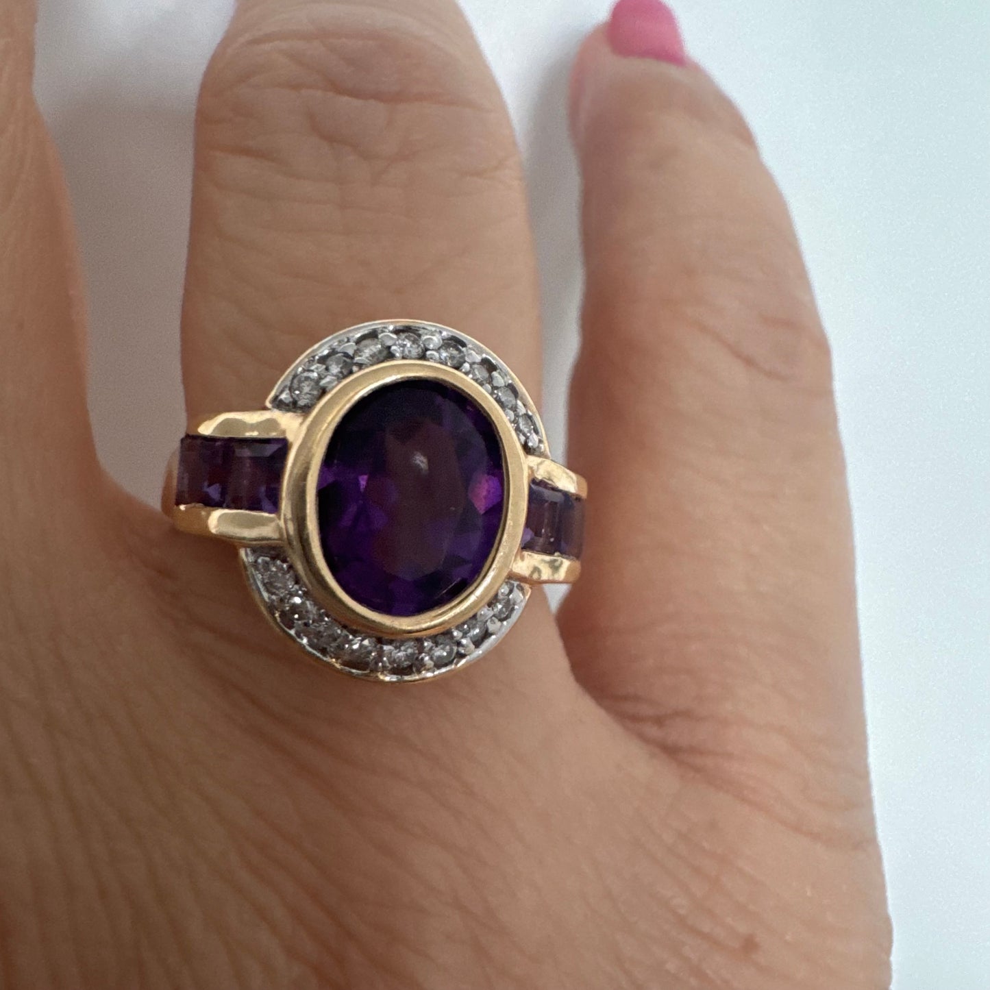 טבעת זהב 14 קראט בעיצוב ייחודי עם אבן אמטיסט אובלית מרכזית בגוון סגול עמוק, משובצת במסגרת חלקה ומודגשת ויהלומים.