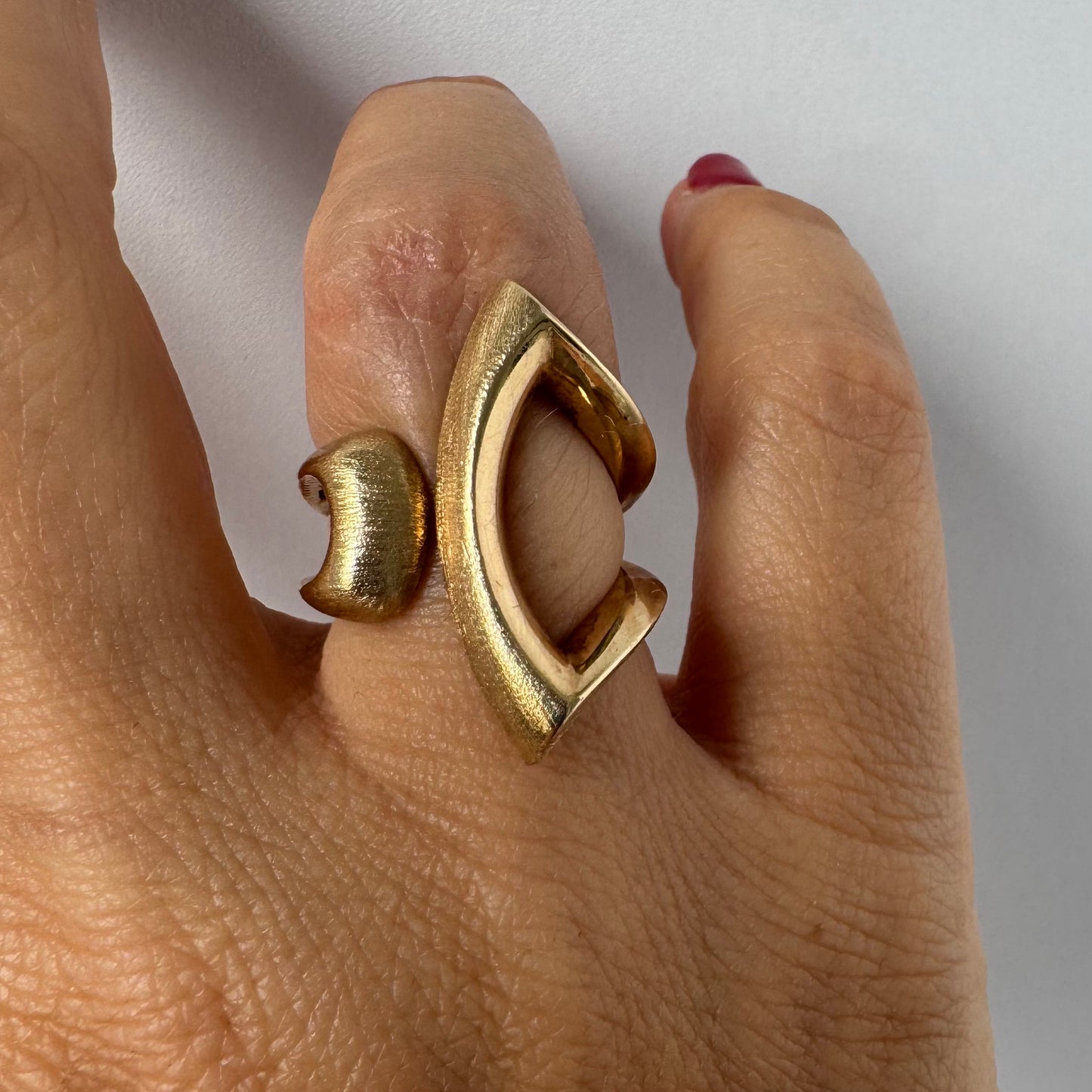14K gold sculptural ring with a bold, modern design featuring flowing, asymmetrical lines.