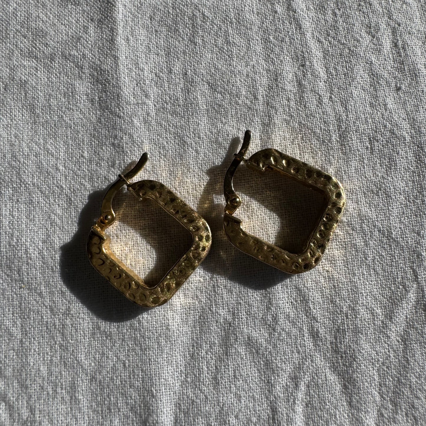 14K gold square hoop earrings with a textured, hammered finish.