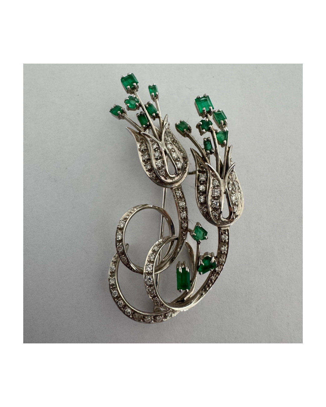 18K gold vintage brooch featuring an elegant floral design set with vibrant Emeralds and sparkling Diamonds.